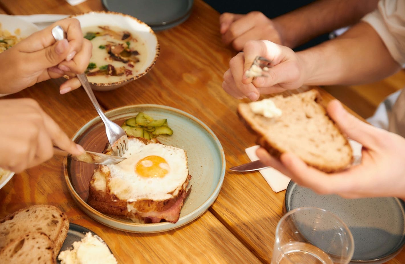 Fried egg and people's hands around