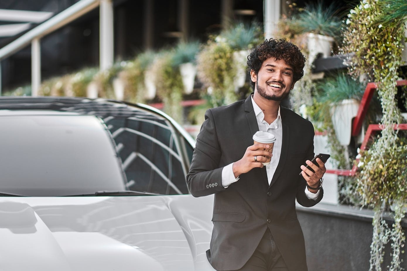 A businessman enjoying a to-go coffee valets his car digitally.