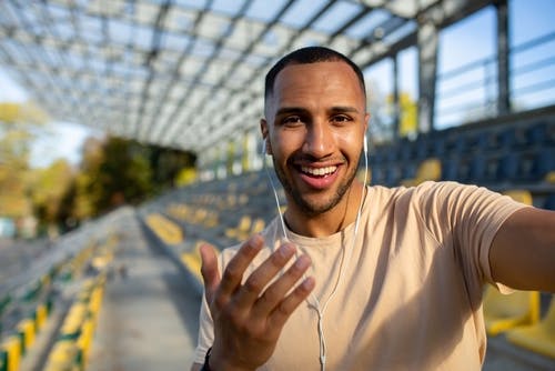 Man in an empty stadium recording his travel experiences on his phone.