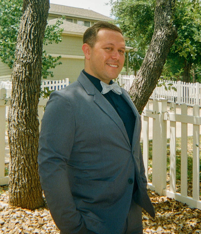 David Reichbach standing in a small park wearing an eye catching suit with his signature bow tie.
