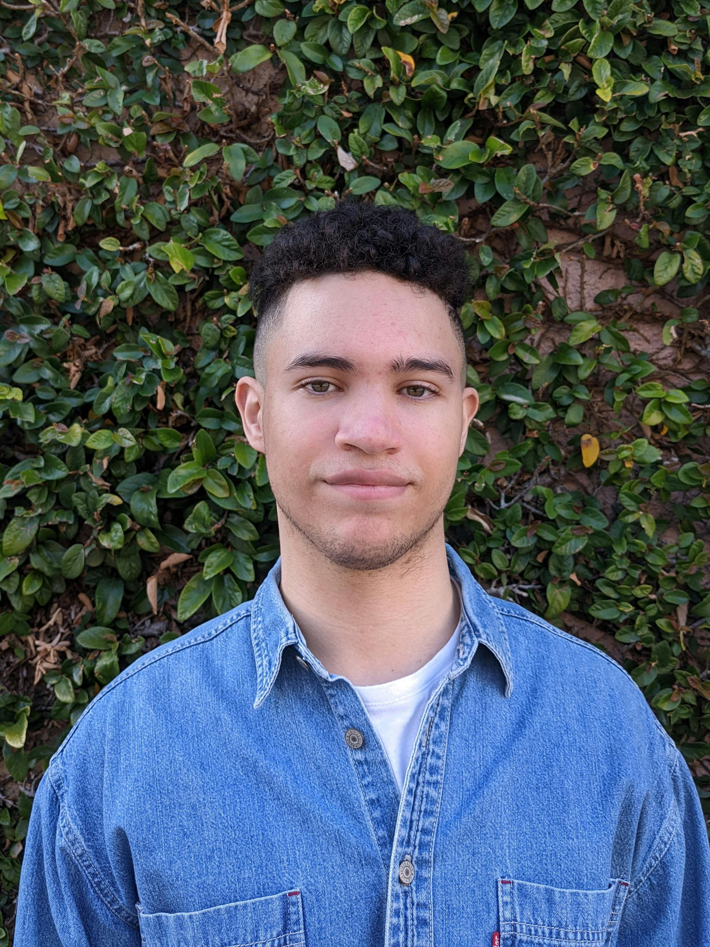 man wearing blue denim shirt and green leafy background