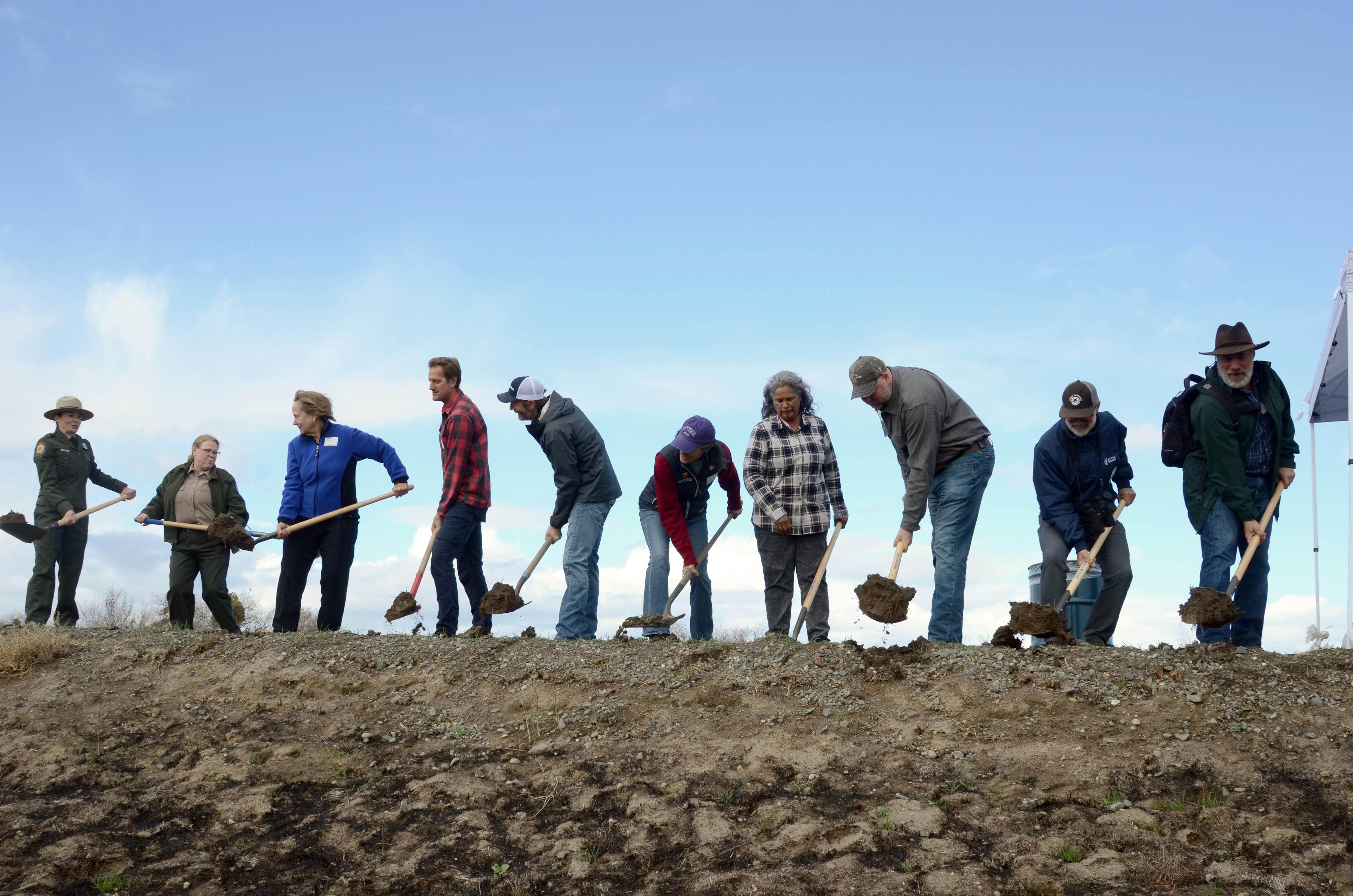 large group of people shoveling dirt 