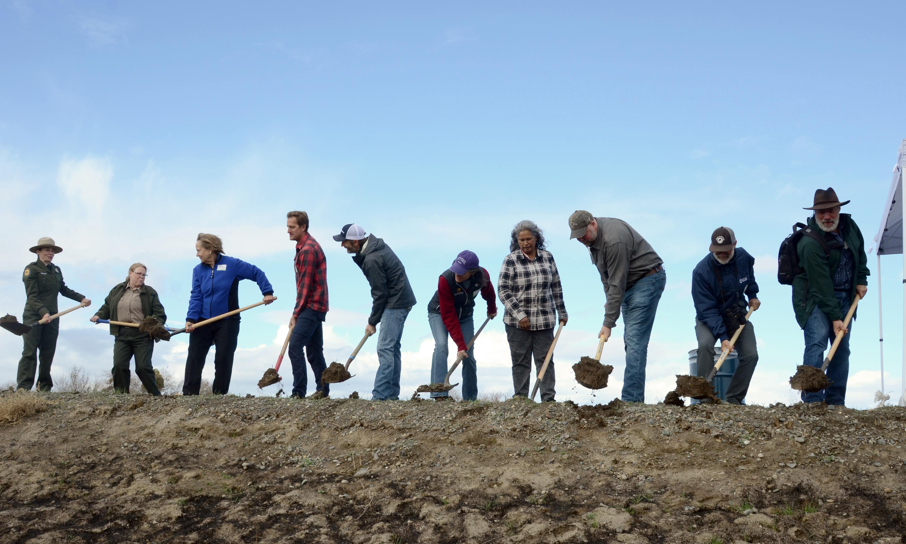 large group of people shoveling dirt