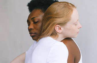 A close-up of a Black woman and a white woman hugging.