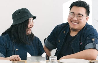 A larger-sized, young Asian couple sitting and smiling together at a table.