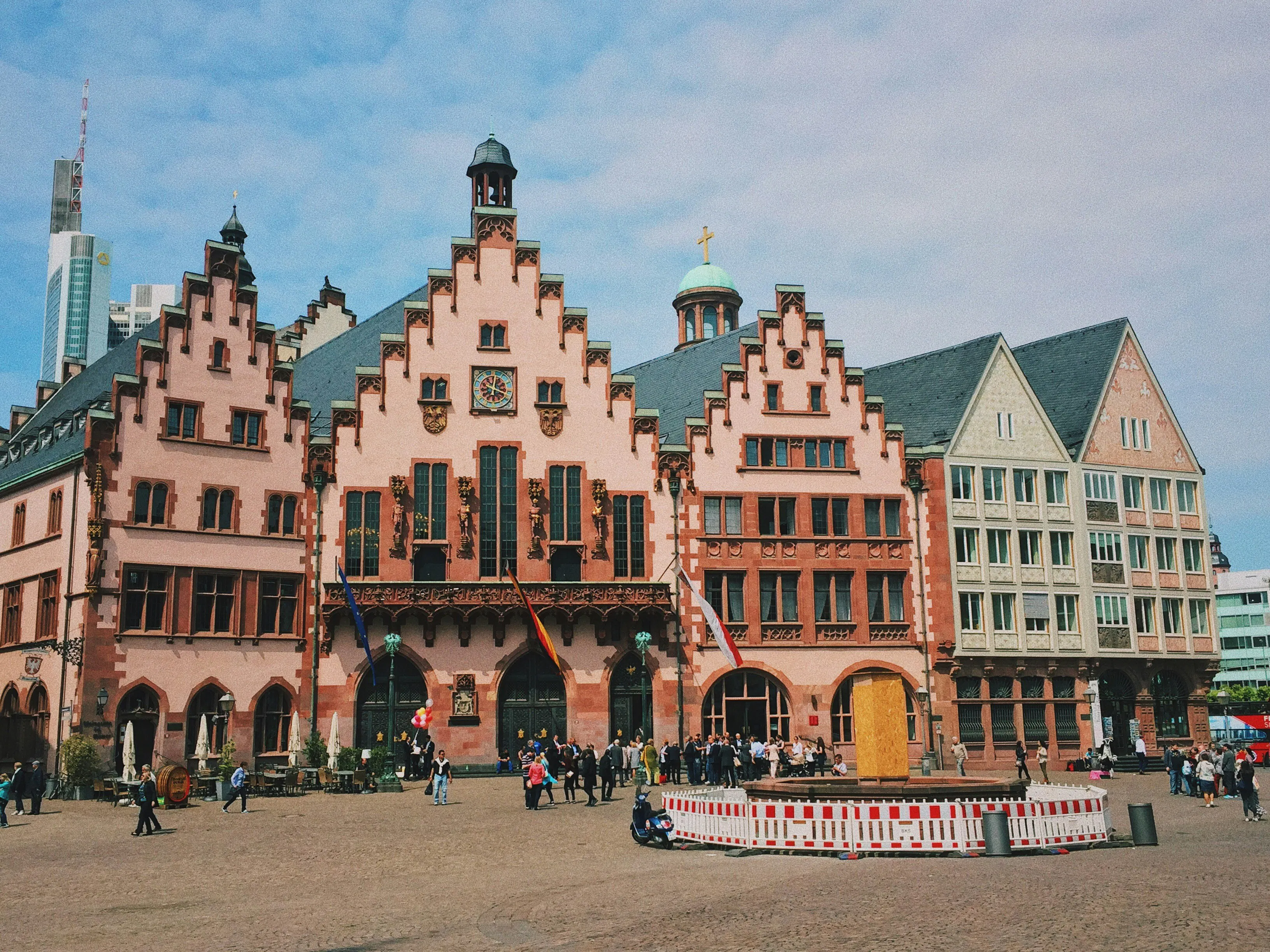 Historic Frankfurt building with stepped gables, decorative stonework, and pedestrians in the plaza.