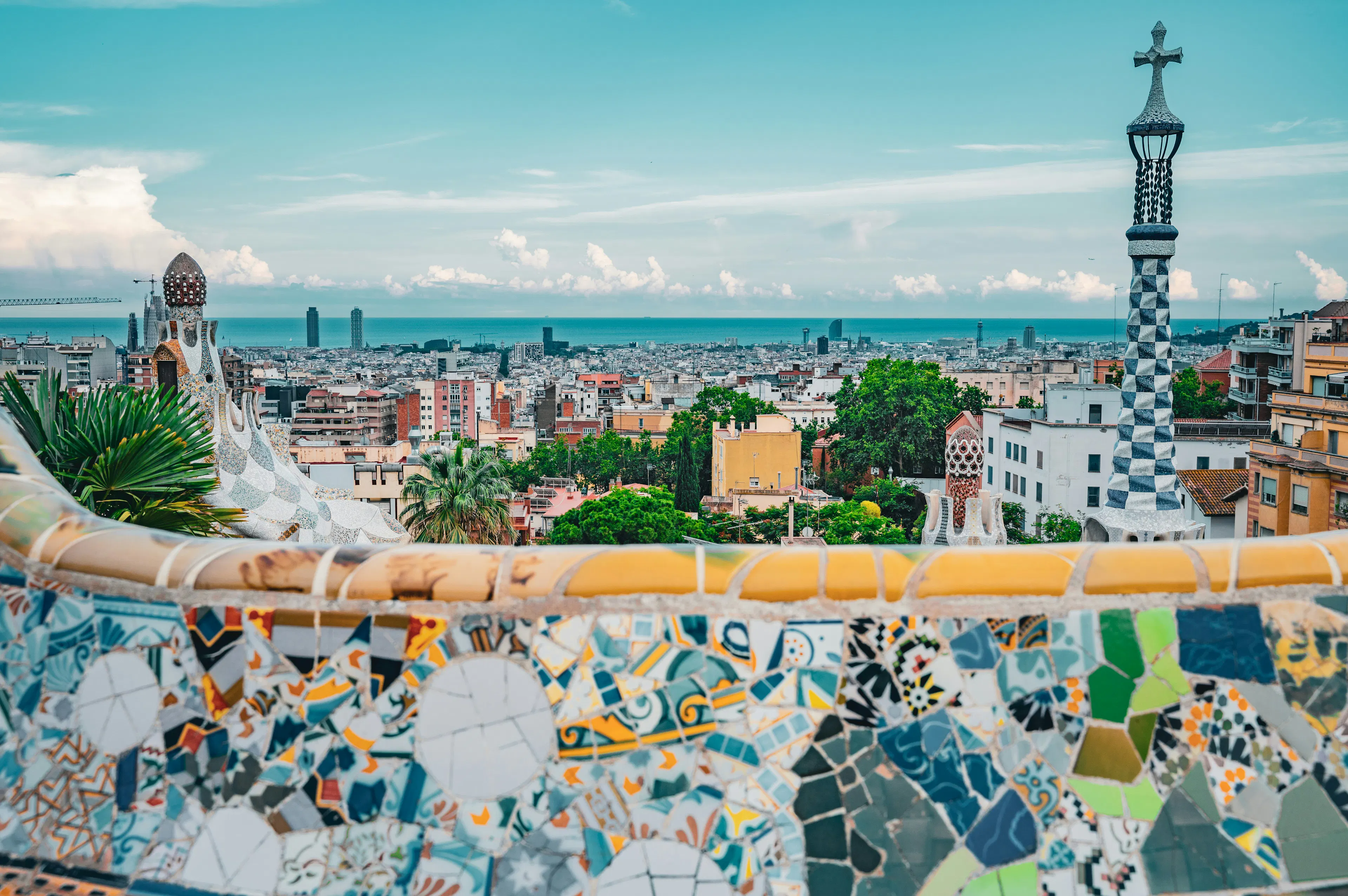 Panoramic view of Barcelona from Park Güell, featuring Gaudí’s colorful mosaic architecture and the city skyline stretching toward the Mediterranean Sea.