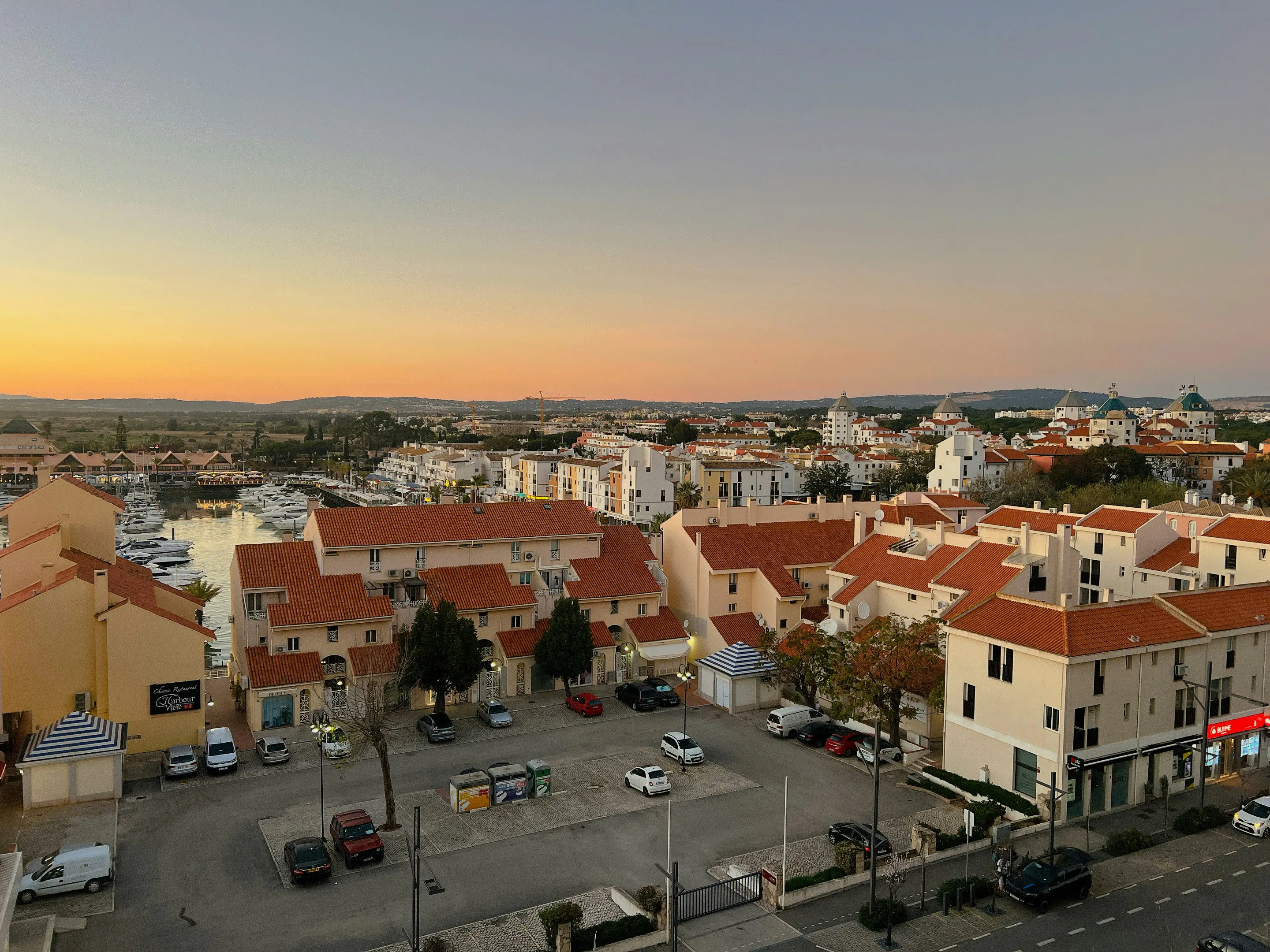Panoramic view of Faro’s historic city center, featuring terracotta rooftops, a public square, and traditional Portuguese architecture at sunset.