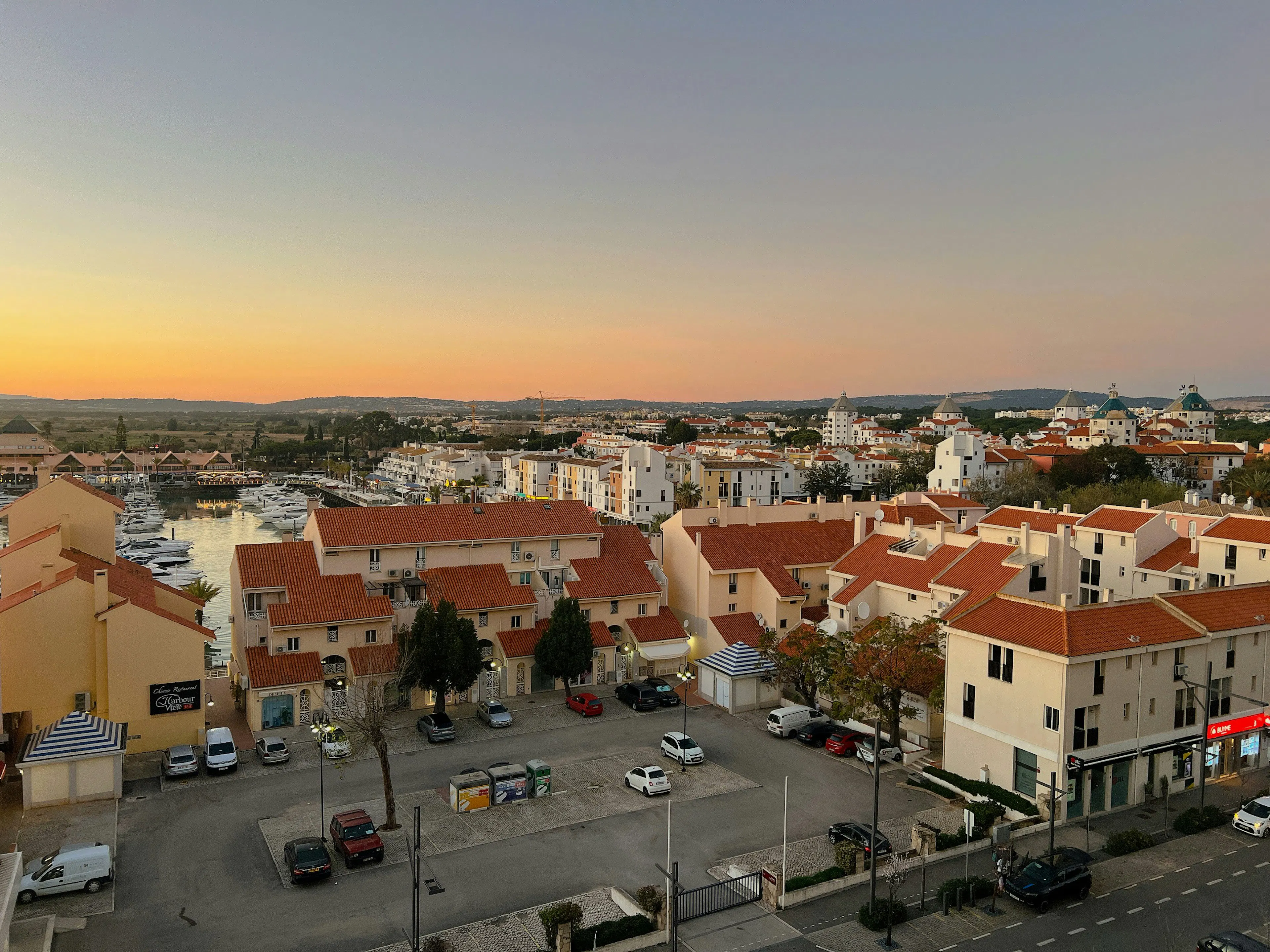 Panoramic view of Faro’s historic city center, featuring terracotta rooftops, a public square, and traditional Portuguese architecture at sunset.