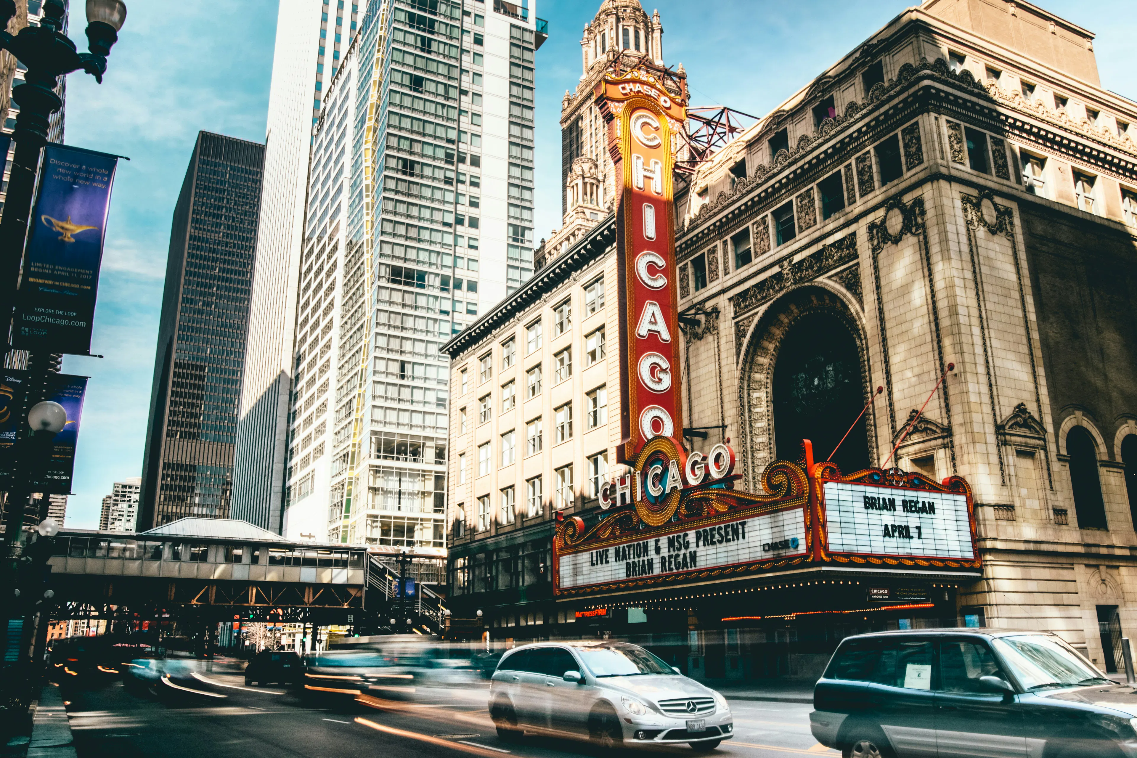 Chicago Theatre marquee above a busy downtown street with traffic and surrounding high-rise buildings.