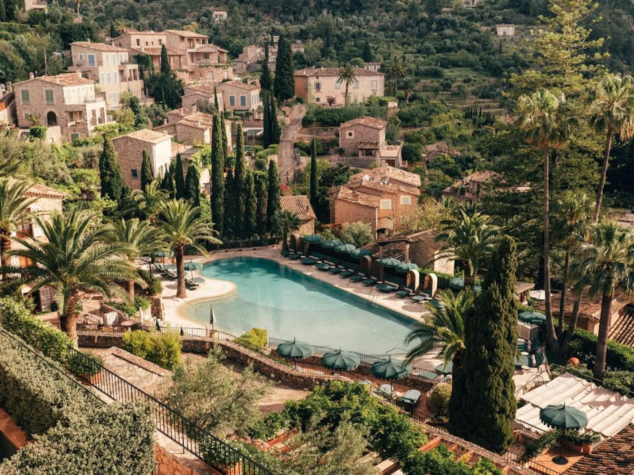 Historic hillside estate with a swimming pool surrounded by gardens and cypress trees.