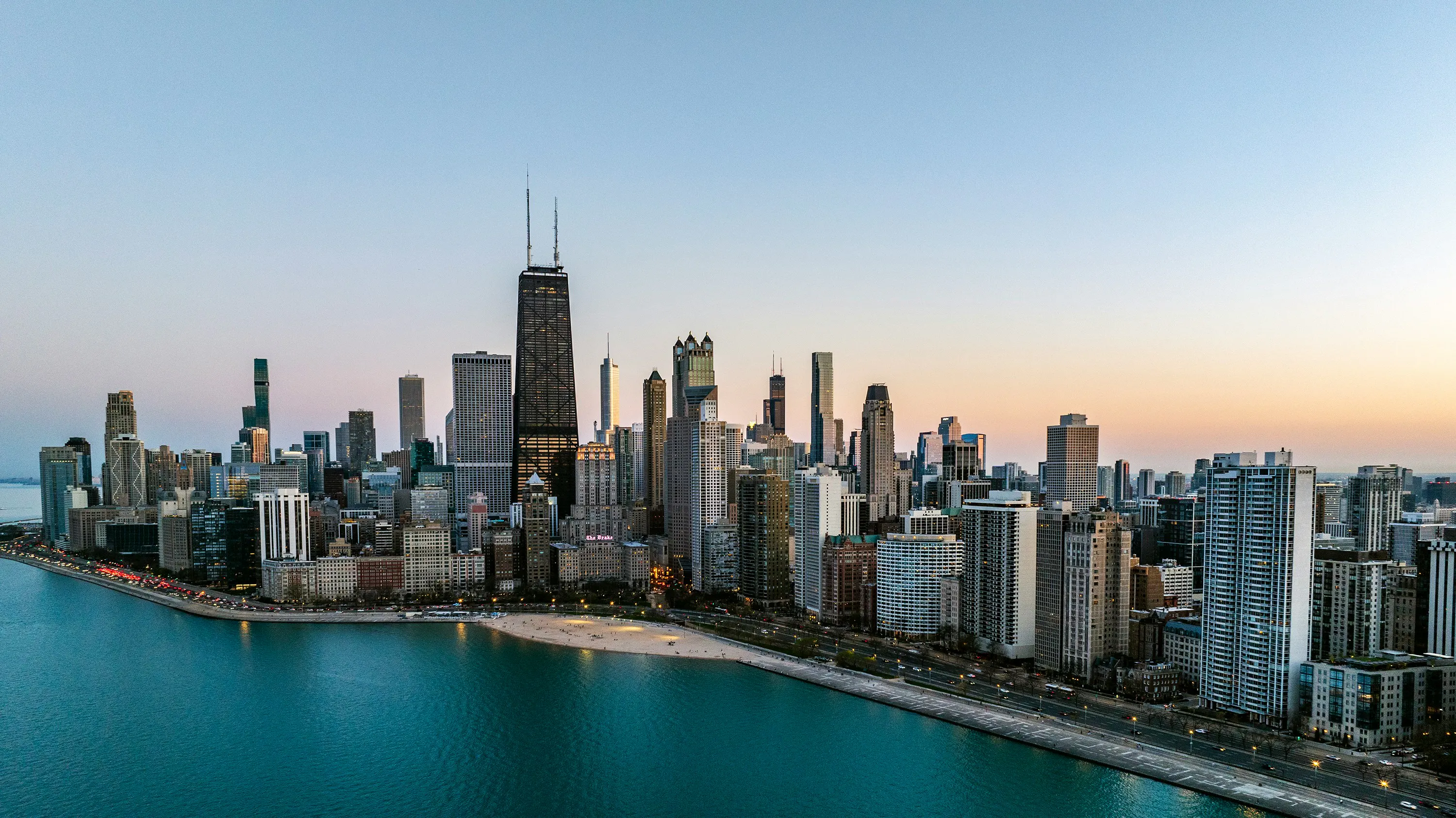 Chicago skyline along Lake Michigan with high-rise buildings, waterfront beaches, and the John Hancock Center at dusk.
