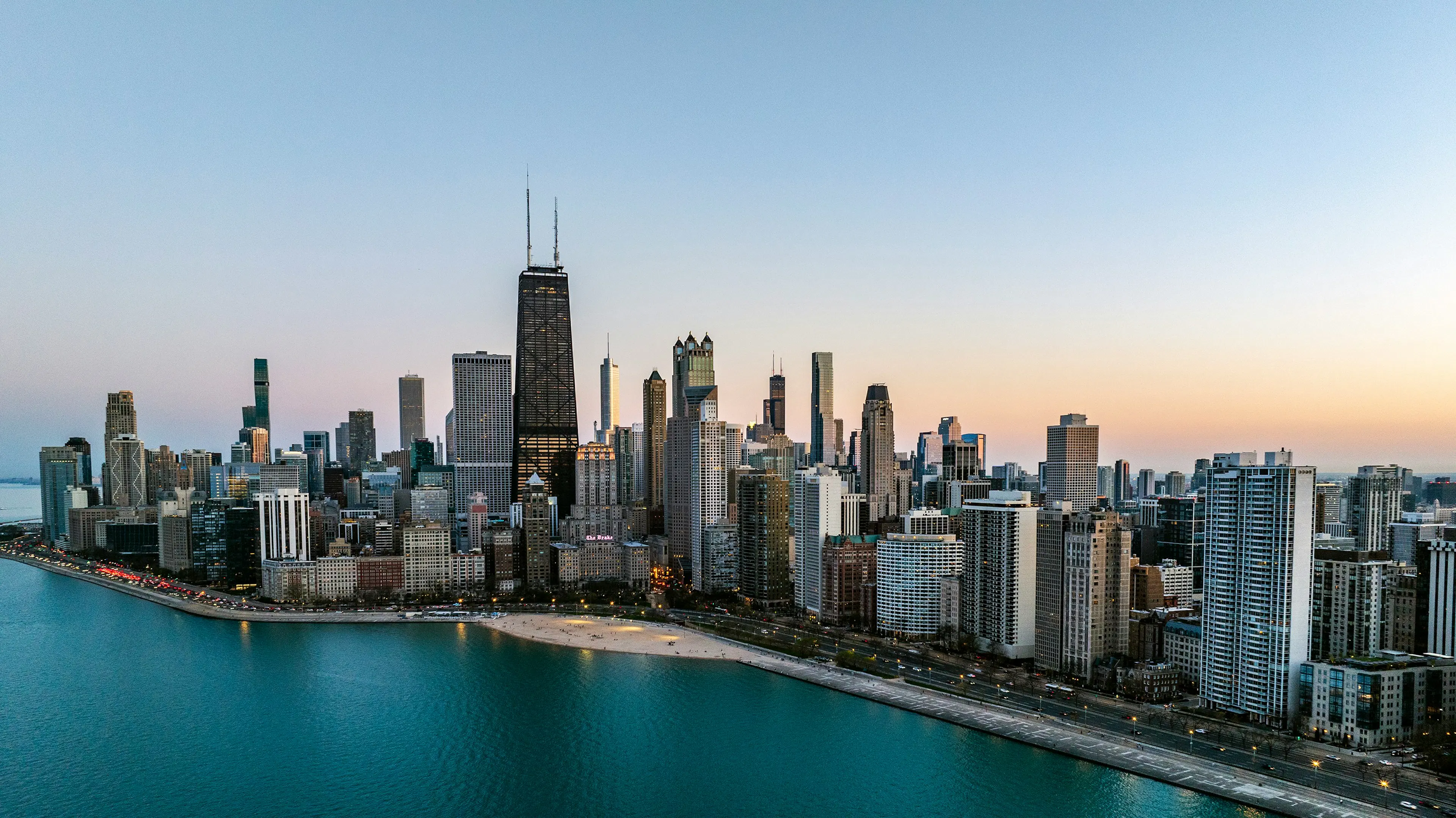 Chicago skyline along Lake Michigan with high-rise buildings, waterfront beaches, and the John Hancock Center at dusk.