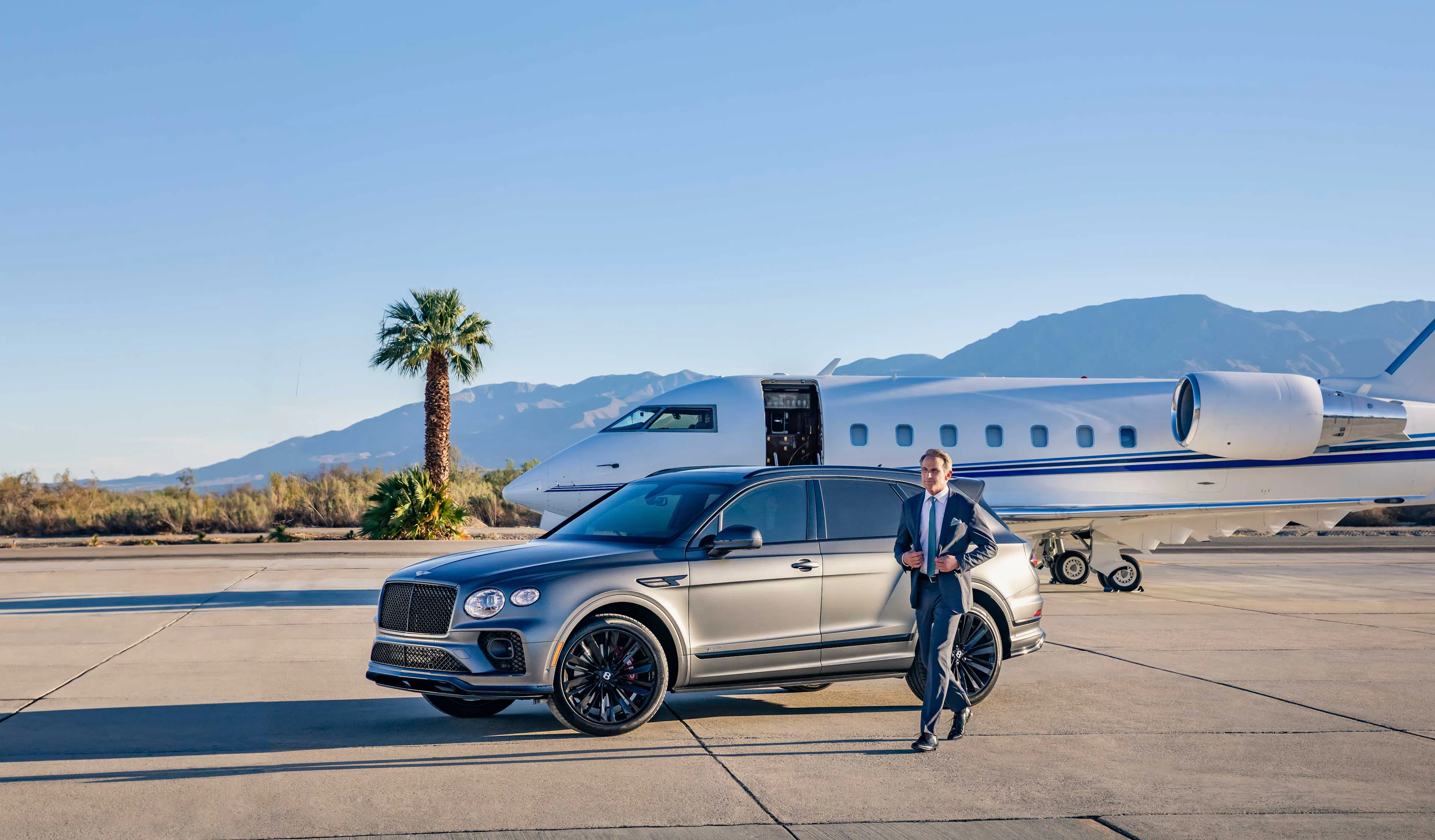 Private jet parked on an airport runway beside a luxury SUV.