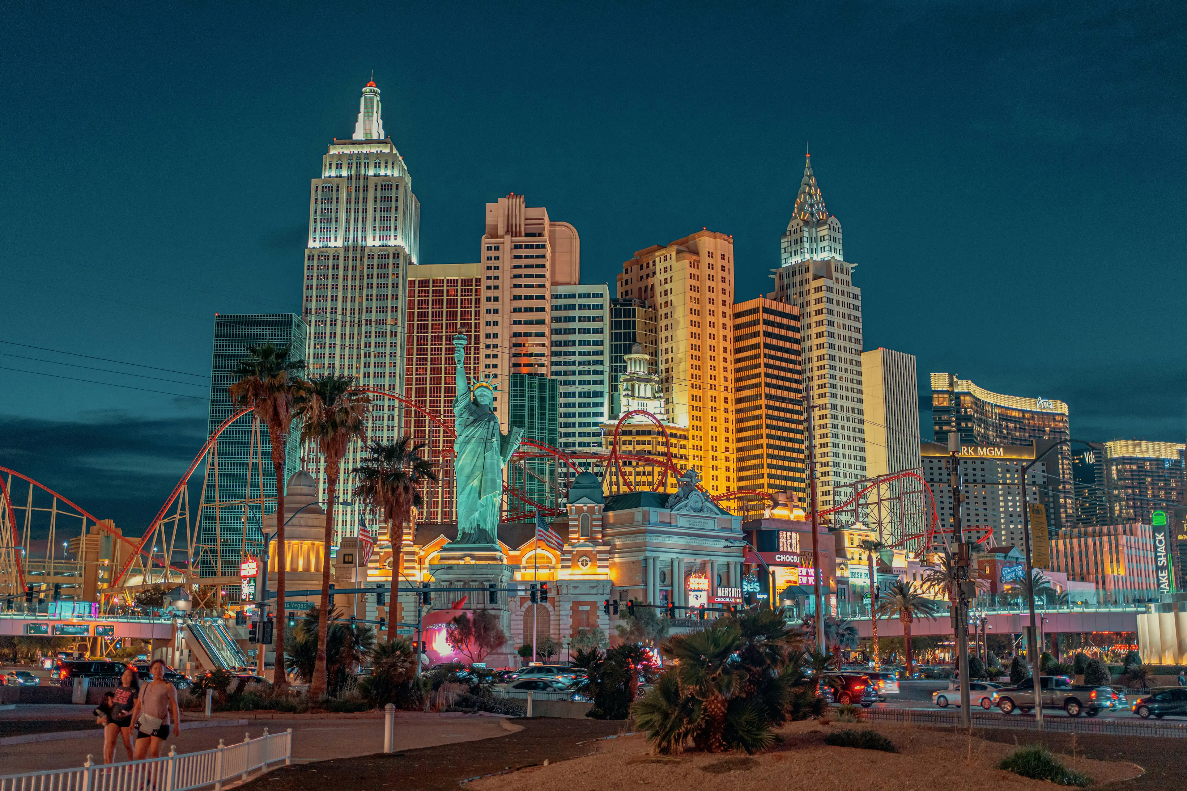 New York-New York Hotel and Casino in Las Vegas with replica skyscrapers, a Statue of Liberty replica, and roller coaster tracks.