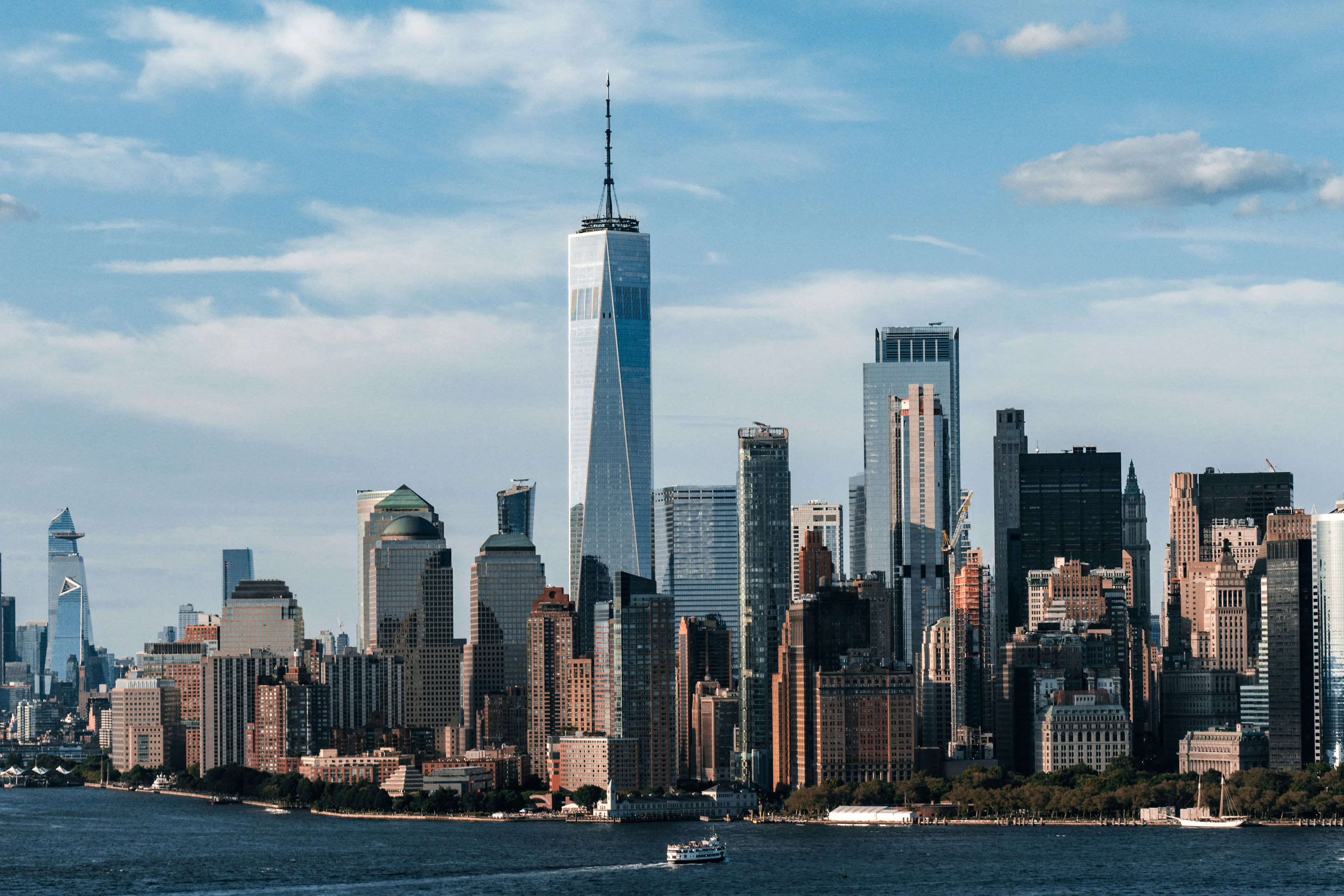 Lower Manhattan skyline with One World Trade Center rising above waterfront skyscrapers.