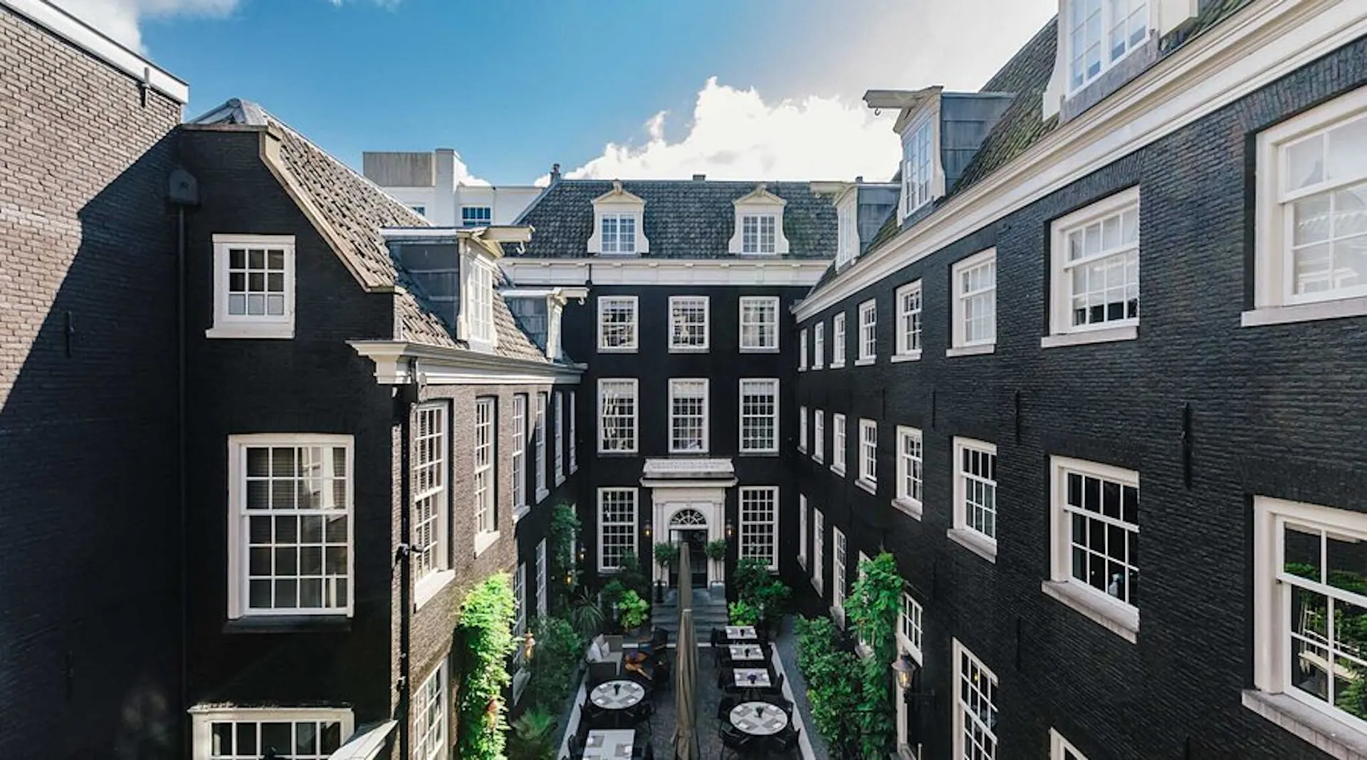 Historic courtyard framed by traditional buildings with a landscaped garden.