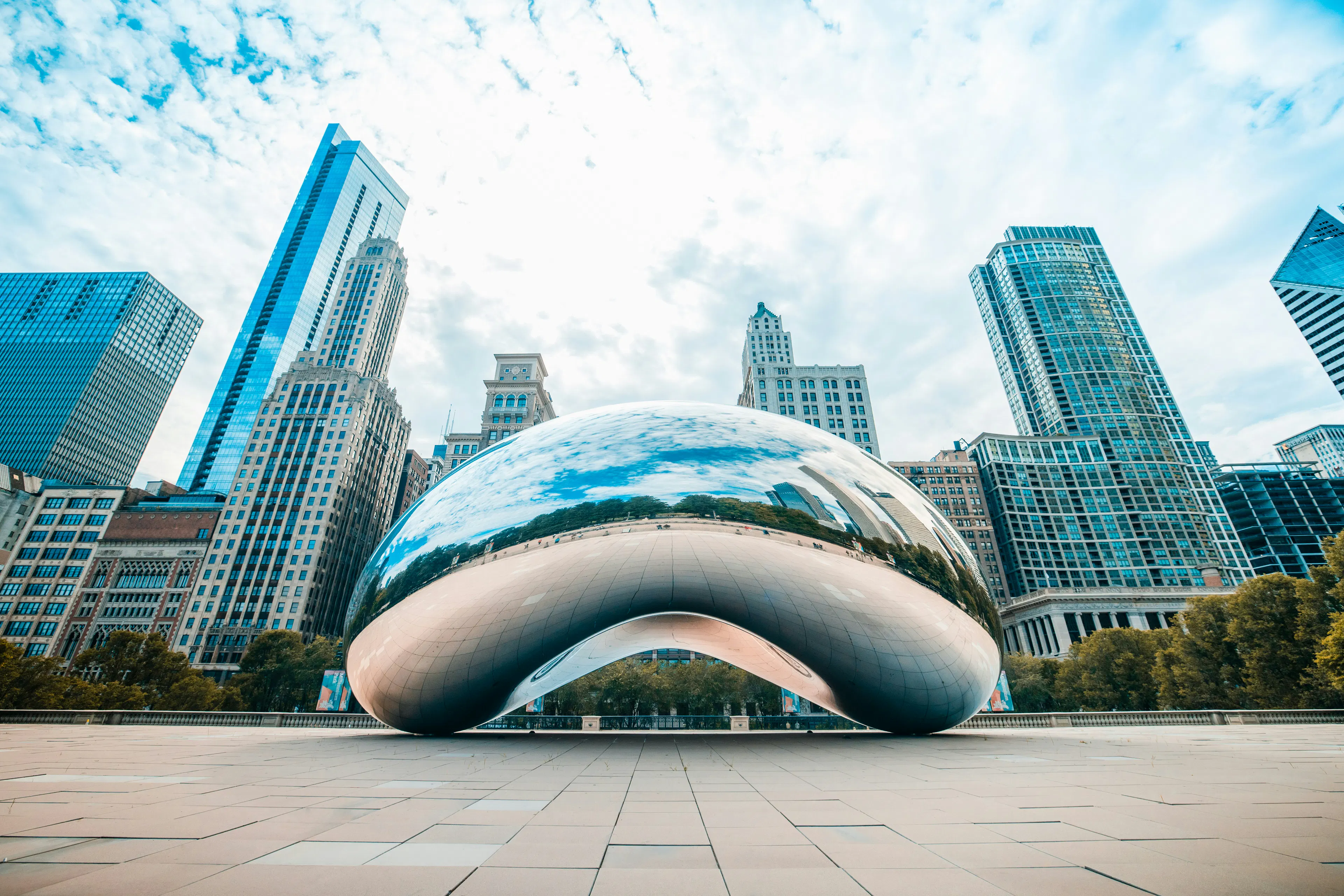 Cloud Gate sculpture in Millennium Park reflecting the Chicago skyline beneath a partly cloudy sky.