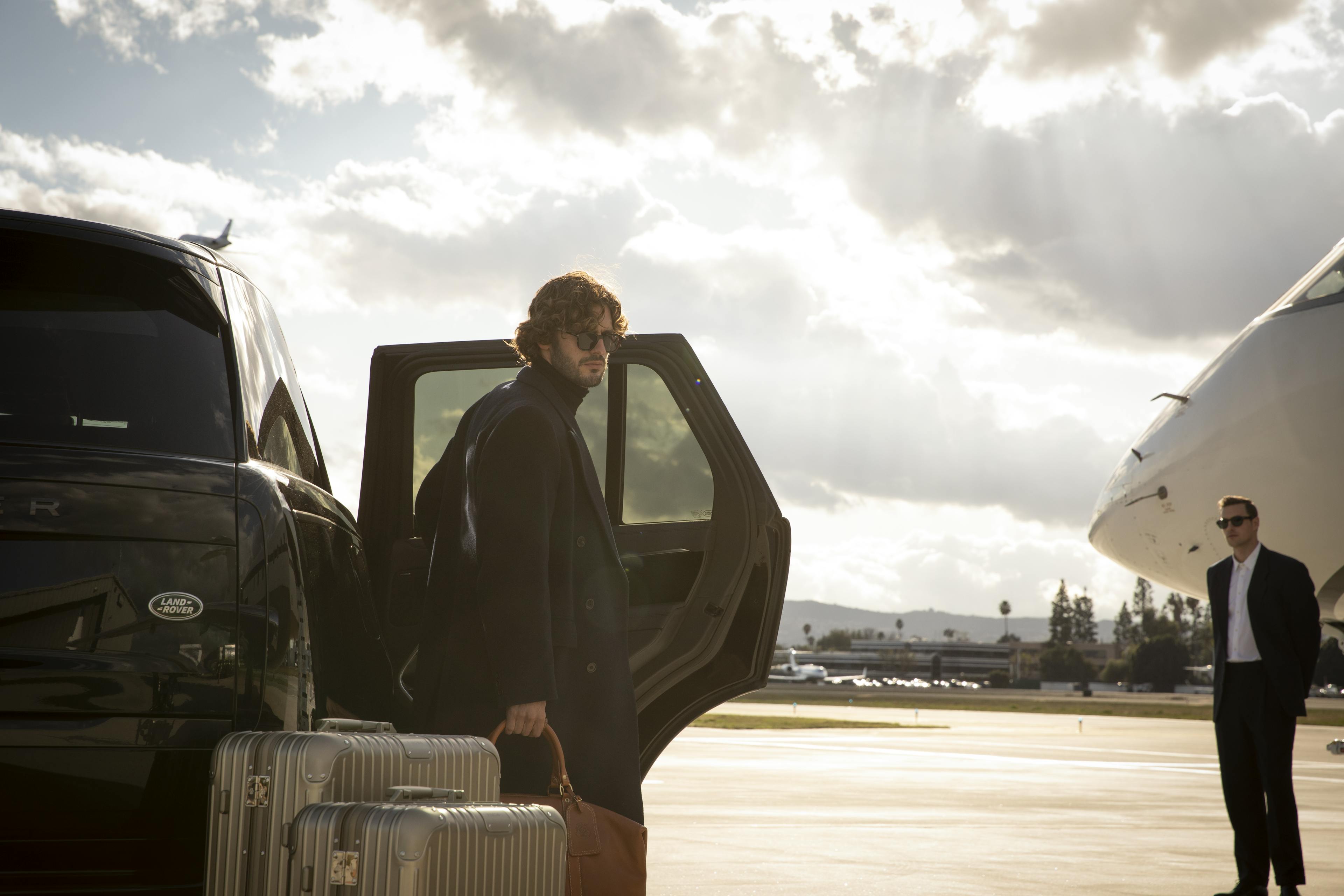 Man exits car with luggage on tarmac ready to board aircraft