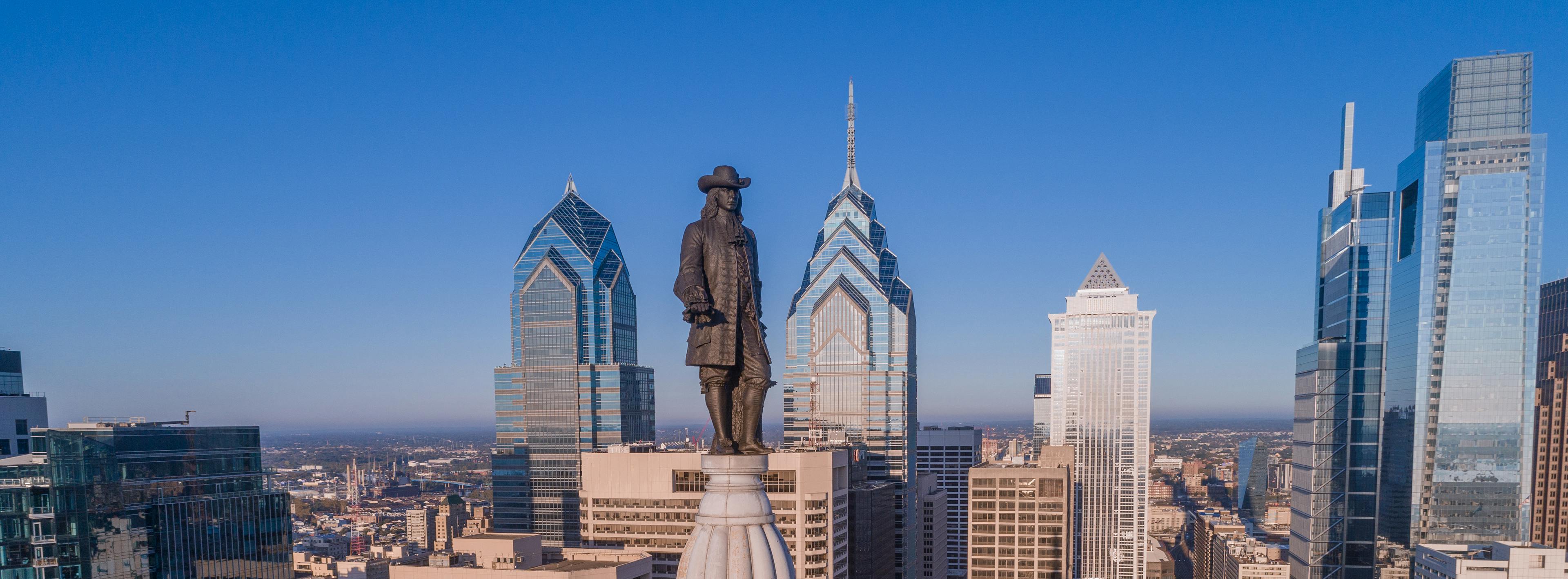 Status a top a building with city skyline in the background