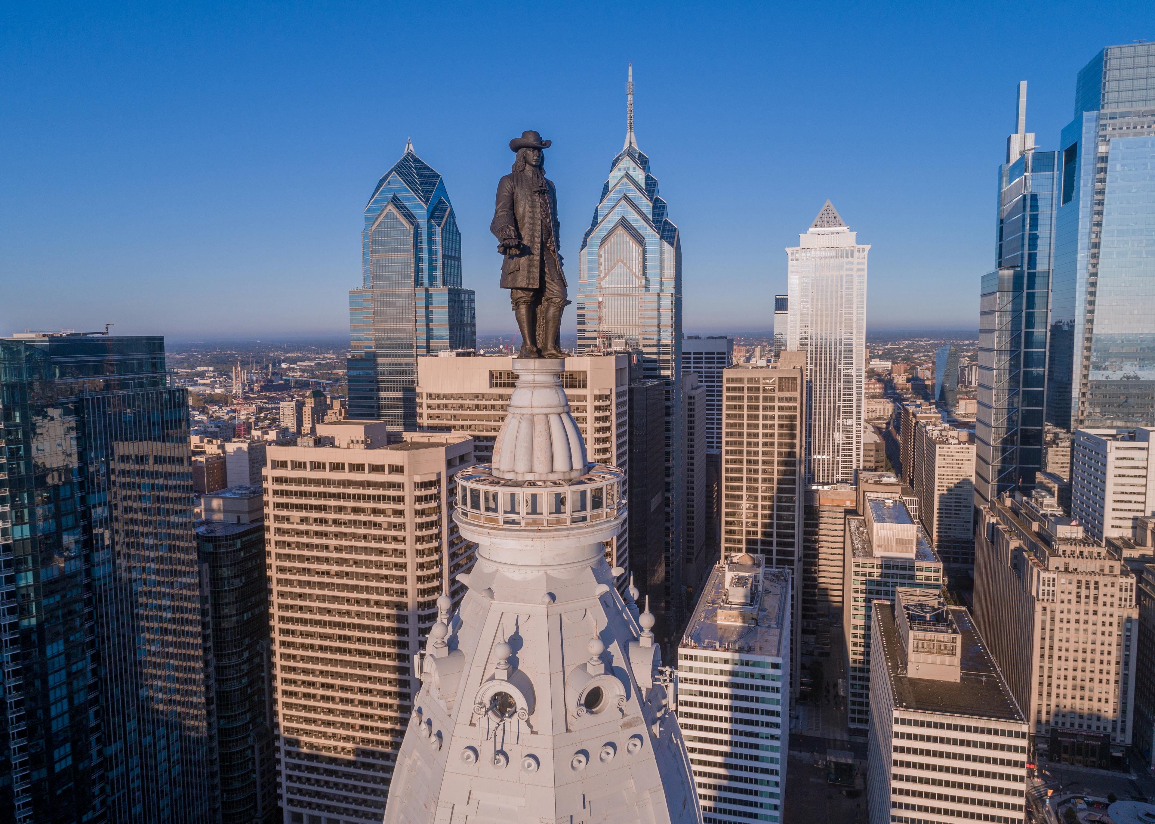 Status a top a building with city skyline in the background