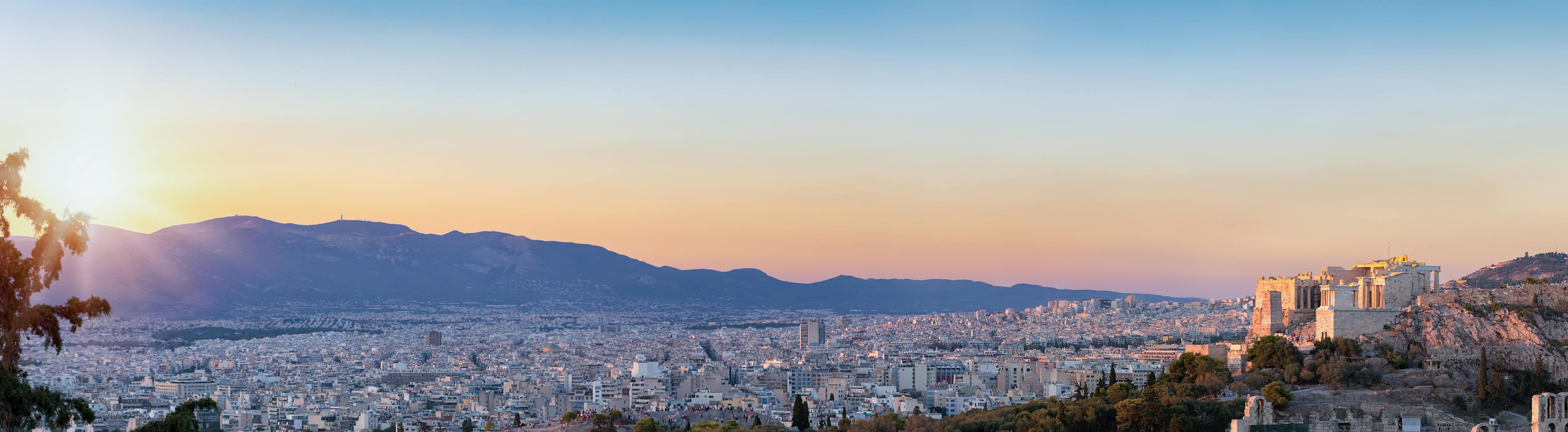 Castle structure sits on top of a mountain with a view of the city in the valley and another mountain on the horizon