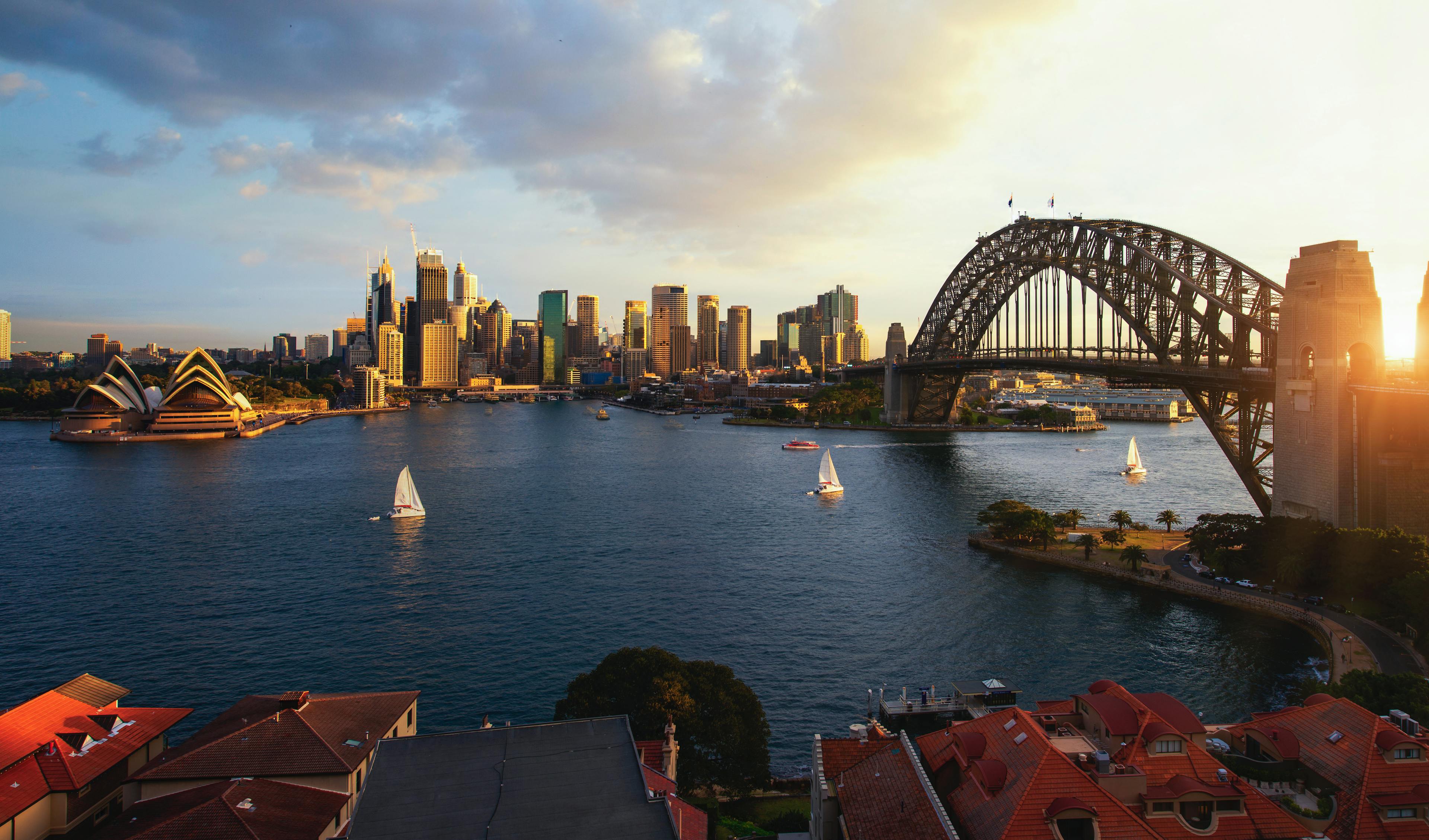 Bridge expanses over a body of water with a city skyline in the background