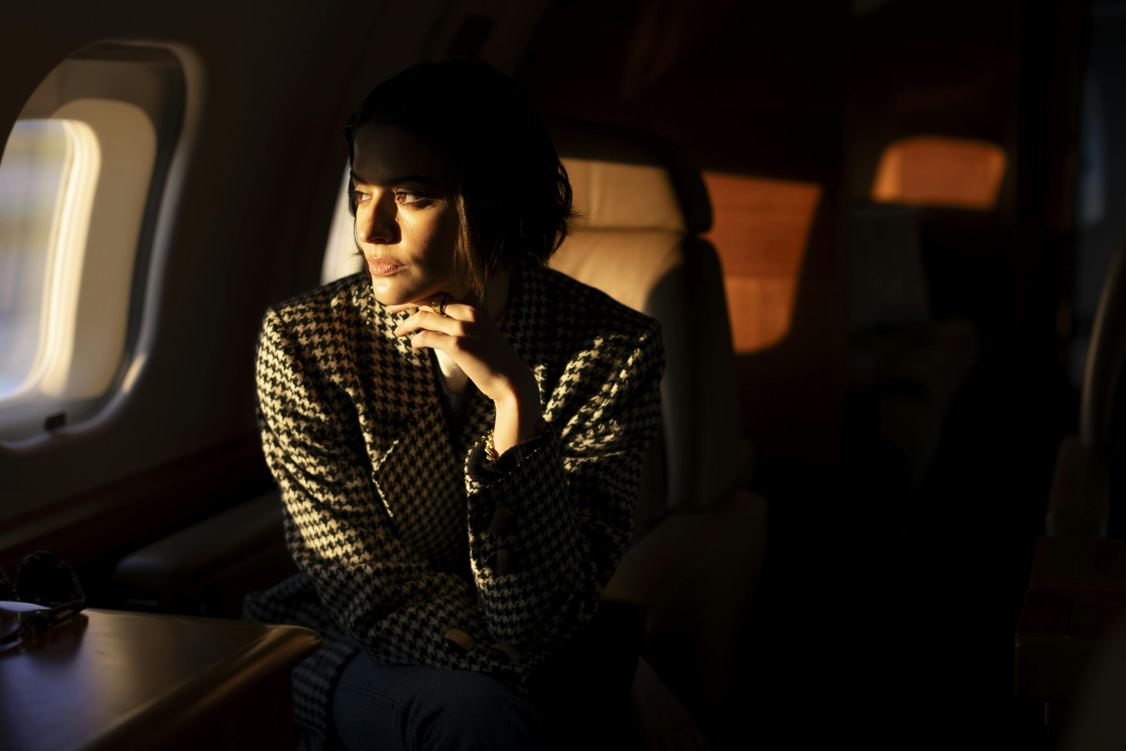 Lady stares out pensively through the jet window