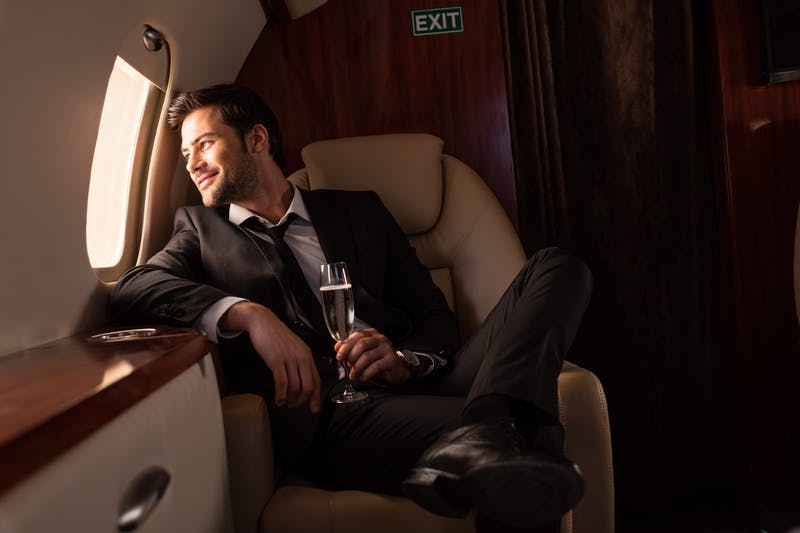 A man smiles, staring out the window of an aircraft