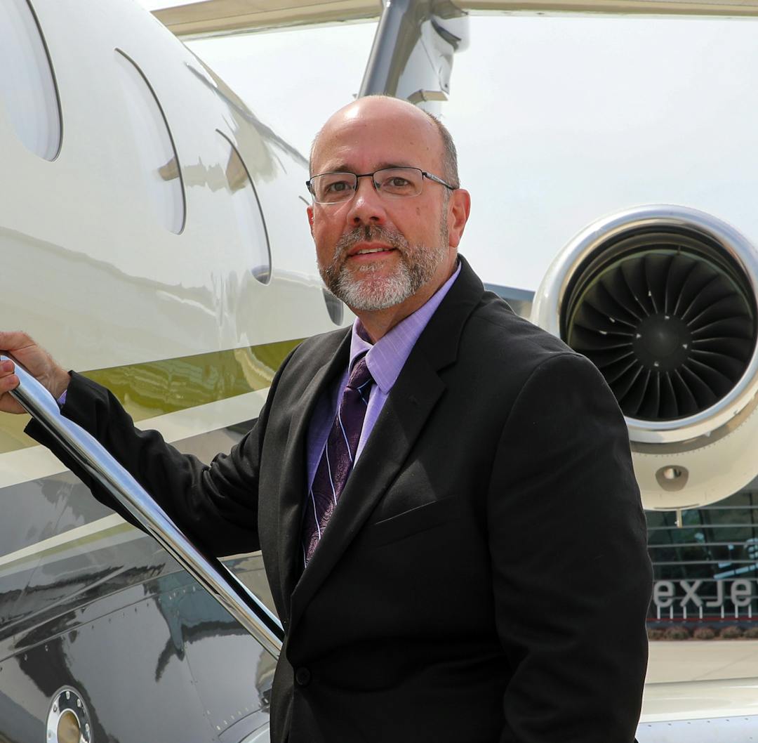 Kent Stauffer posing at the base of the stair of a Flexjet Aircraft