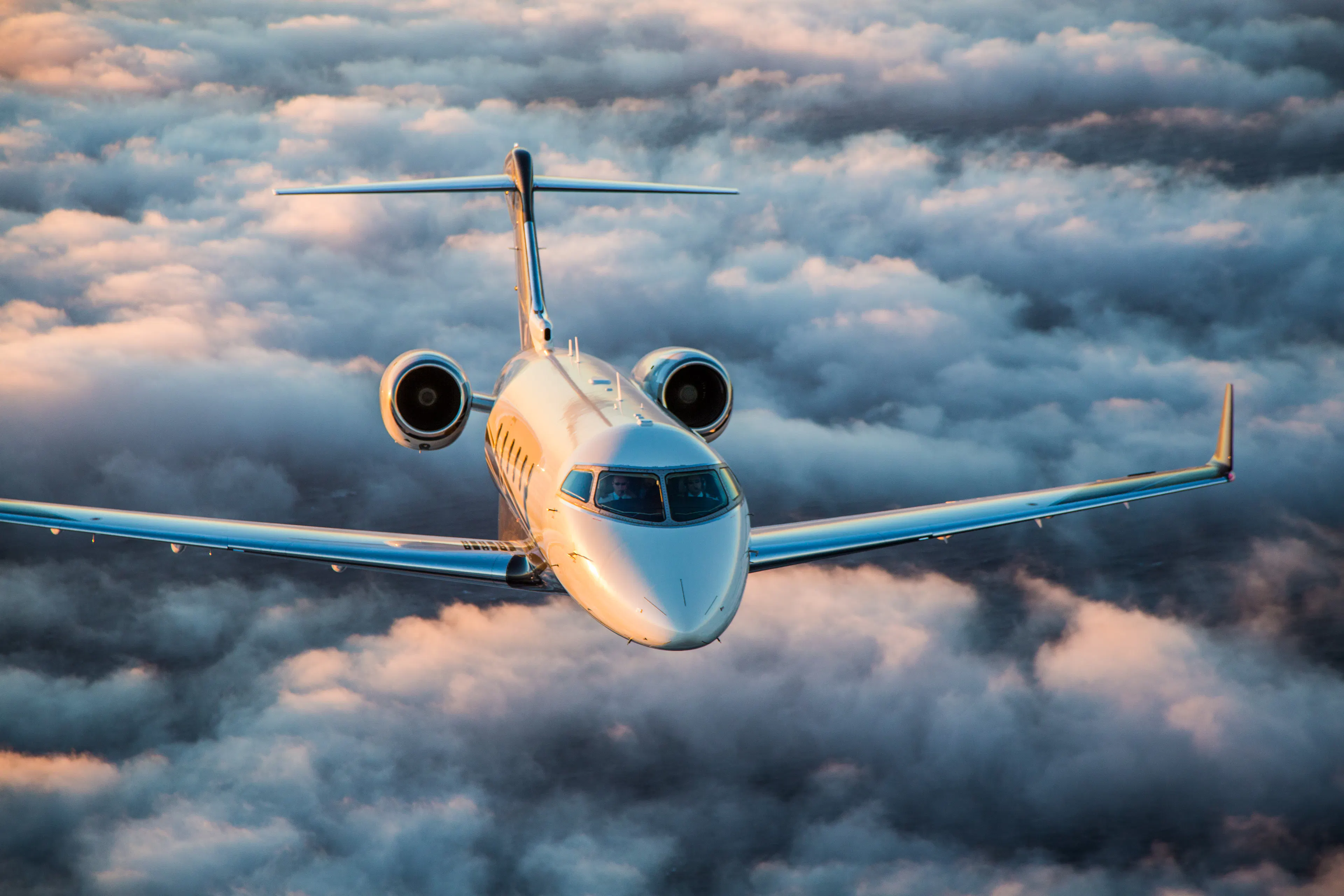 an FXAIR Challenger aircraft flying towards the camera with golden hour clouds behind