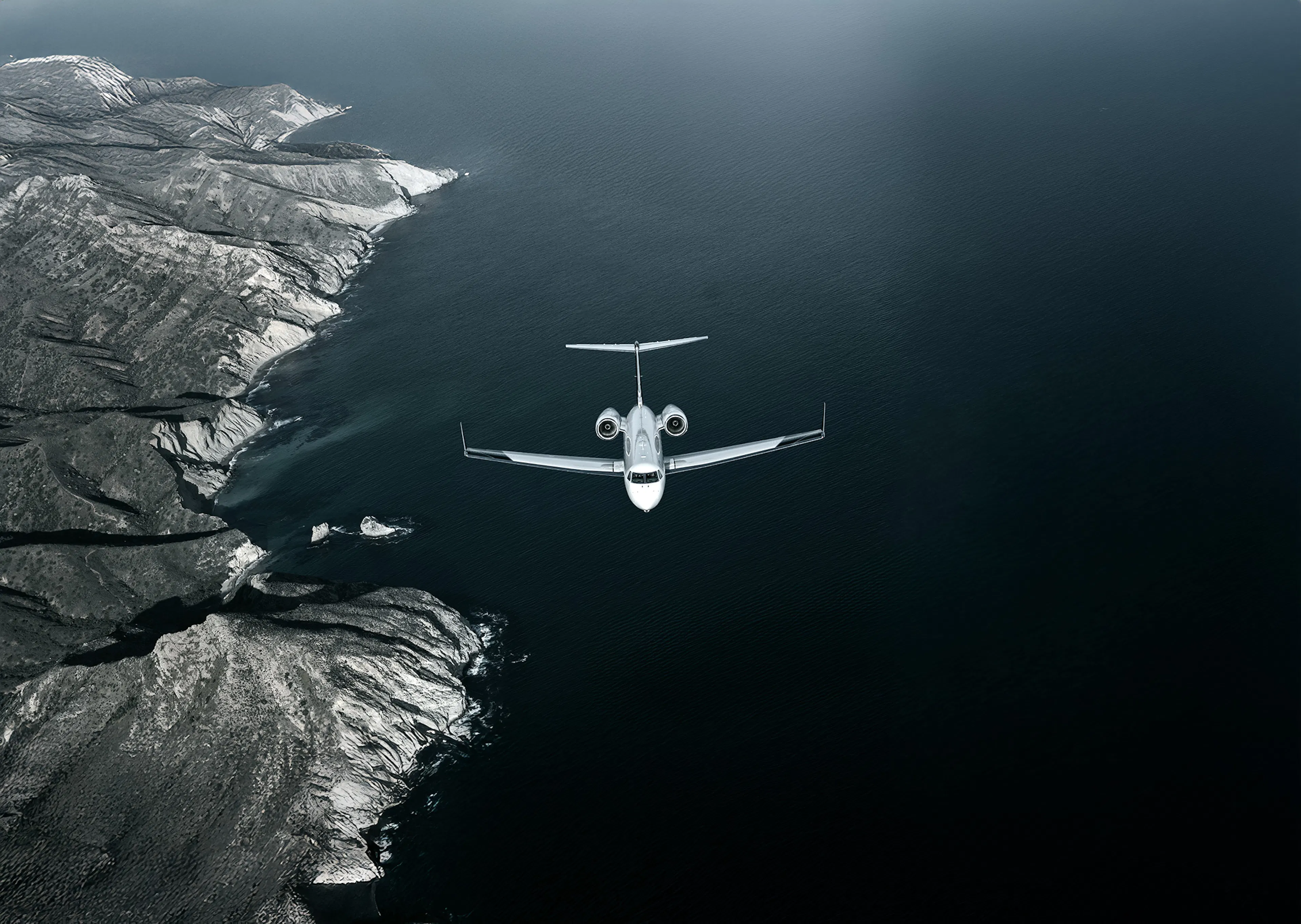 A Gulfstream G450 flying below with the ocean and land below