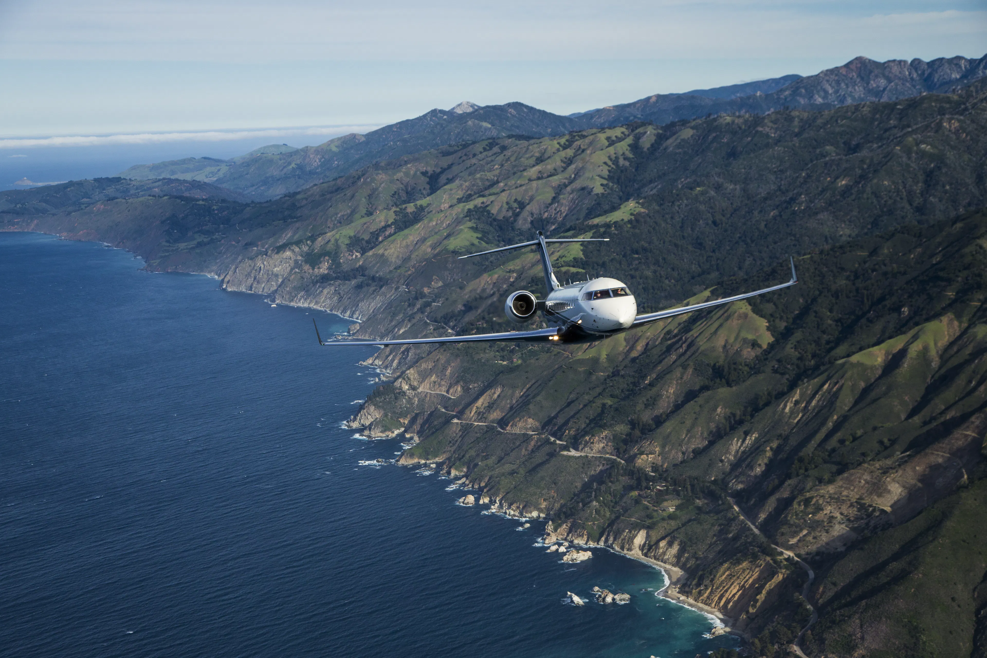 A private jet flying over a rocky coastline