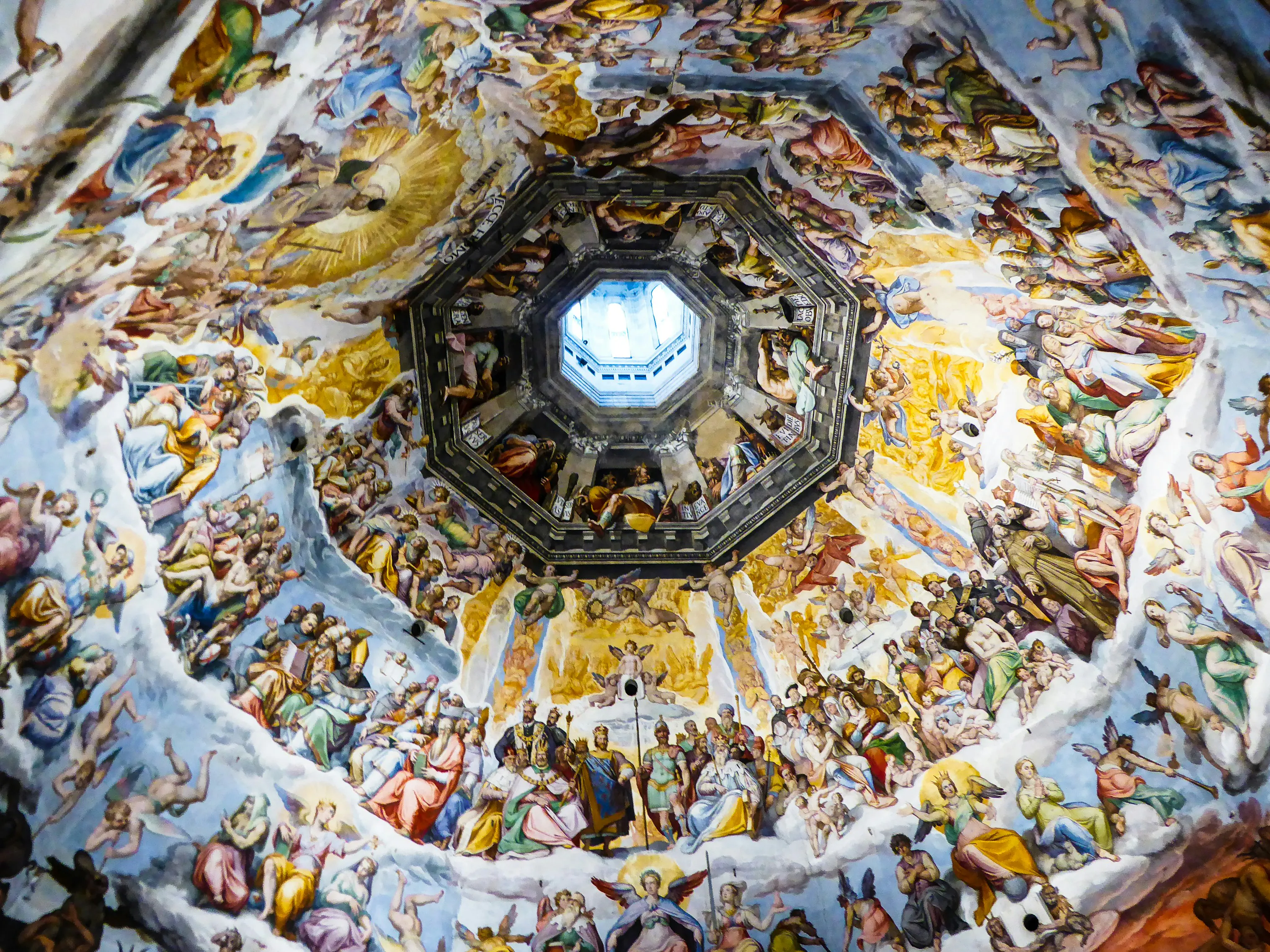 Painted dome ceiling in Florence Cathedral featuring religious frescoes surrounding an octagonal skylight.