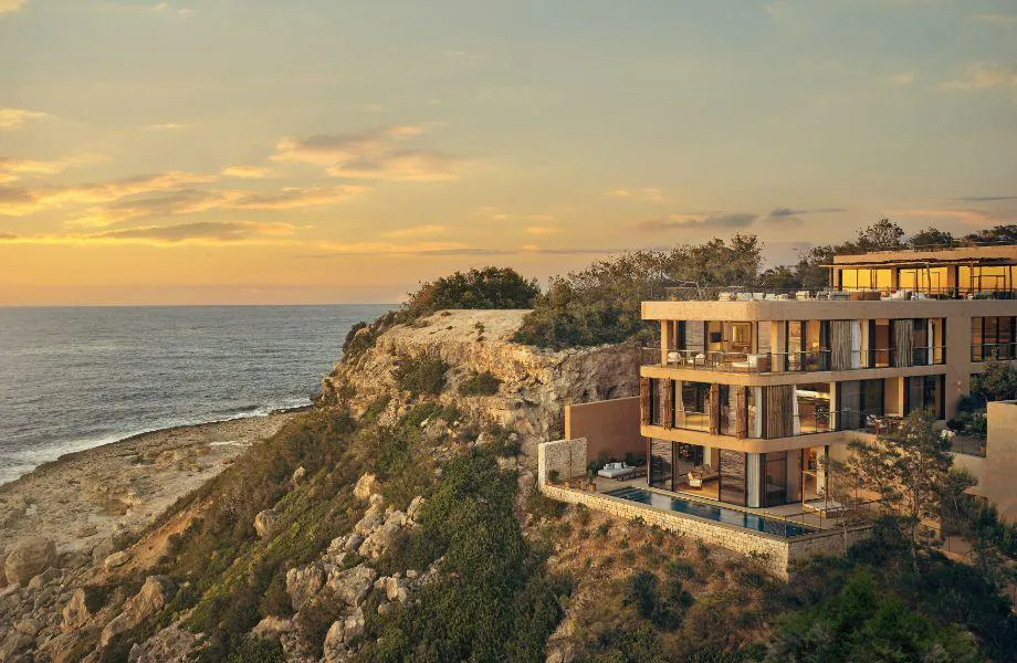 Luxury cliffside resort overlooking the ocean at sunset.