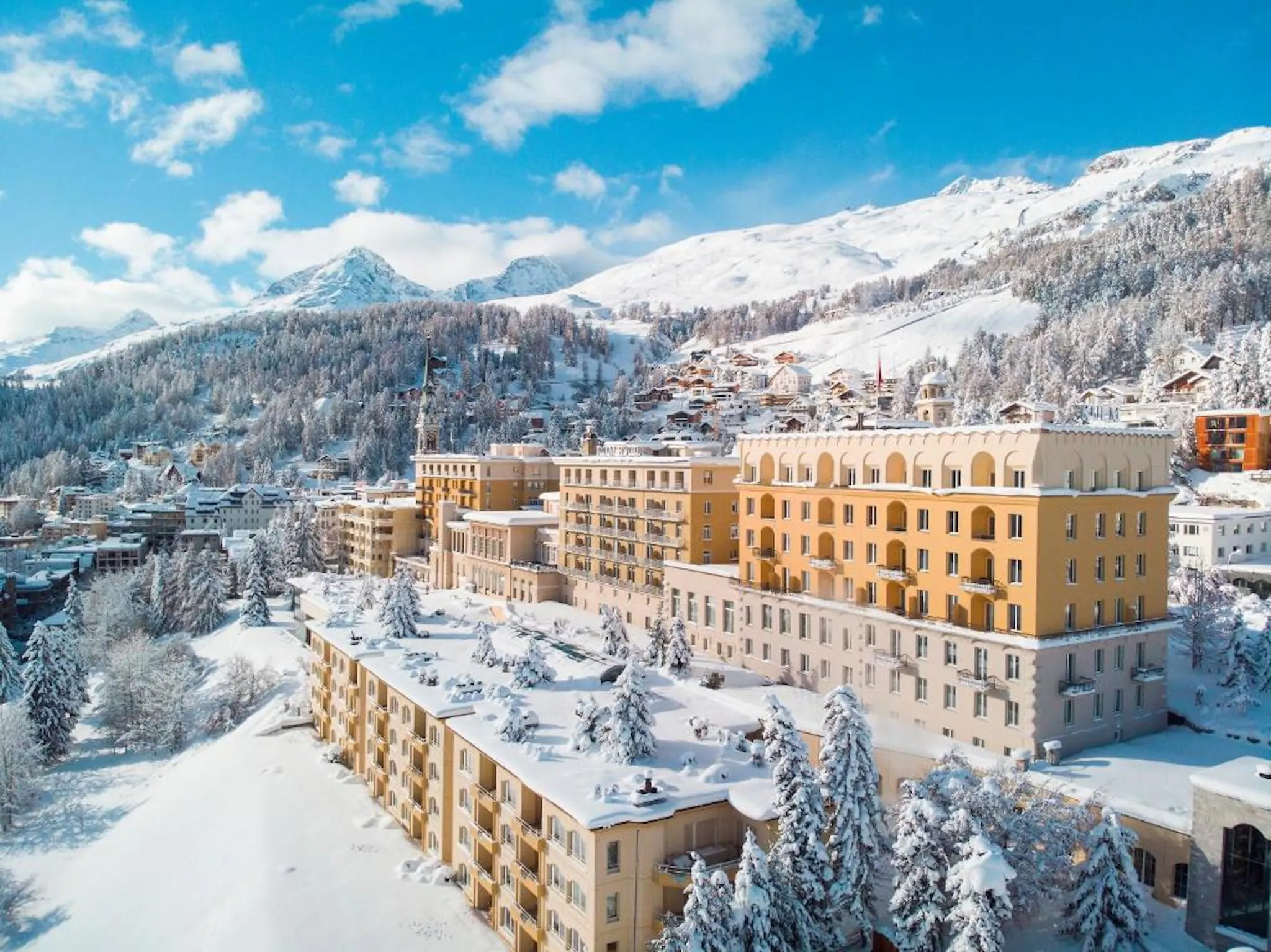 Luxury mountain resort surrounded by snow-covered trees and alpine peaks.