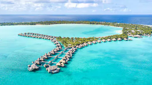 Overwater villas extending from a tropical island into turquoise waters.