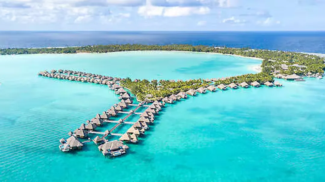 Overwater villas extending from a tropical island into turquoise waters.