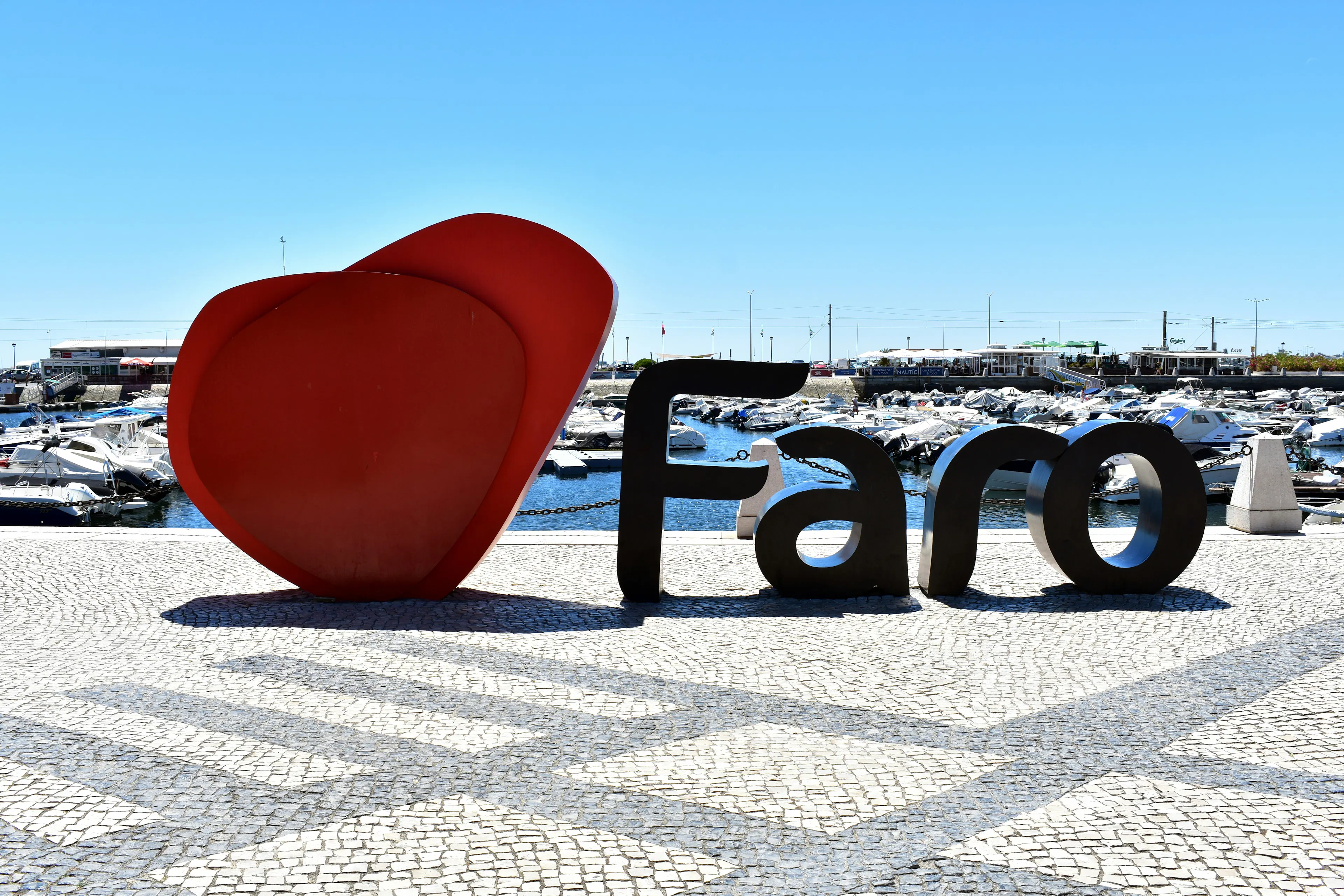 I Love Faro” waterfront sign overlooking a marina with boats and clear blue skies.