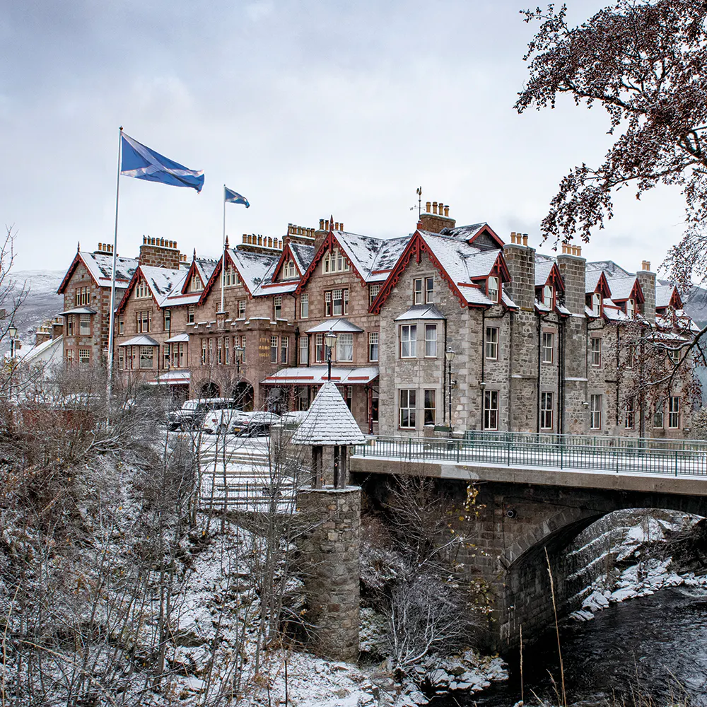 Historic castle-style hotel beside a bridge in a snowy landscape.