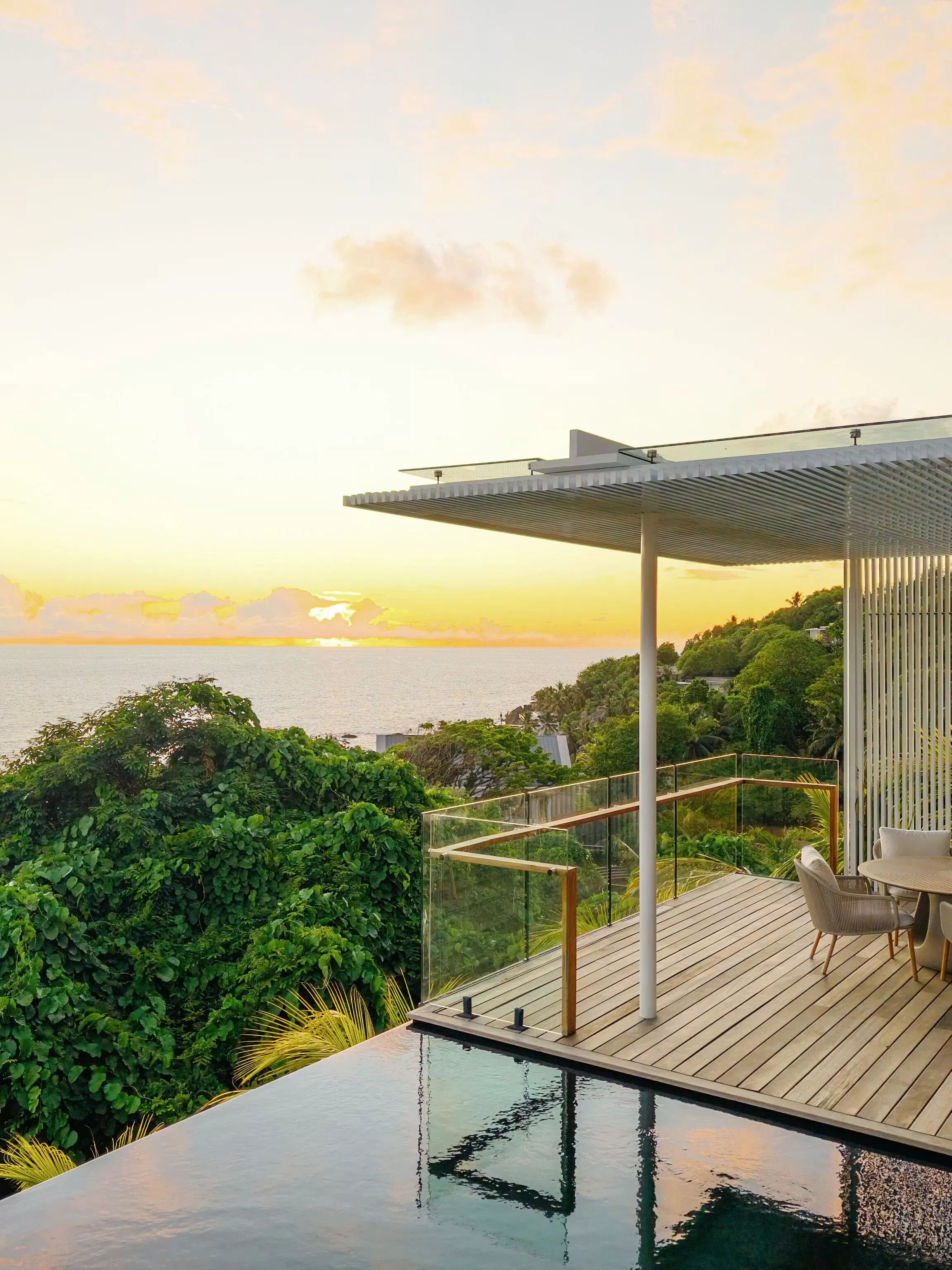 Modern outdoor patio overlooking lush greenery at sunset.
