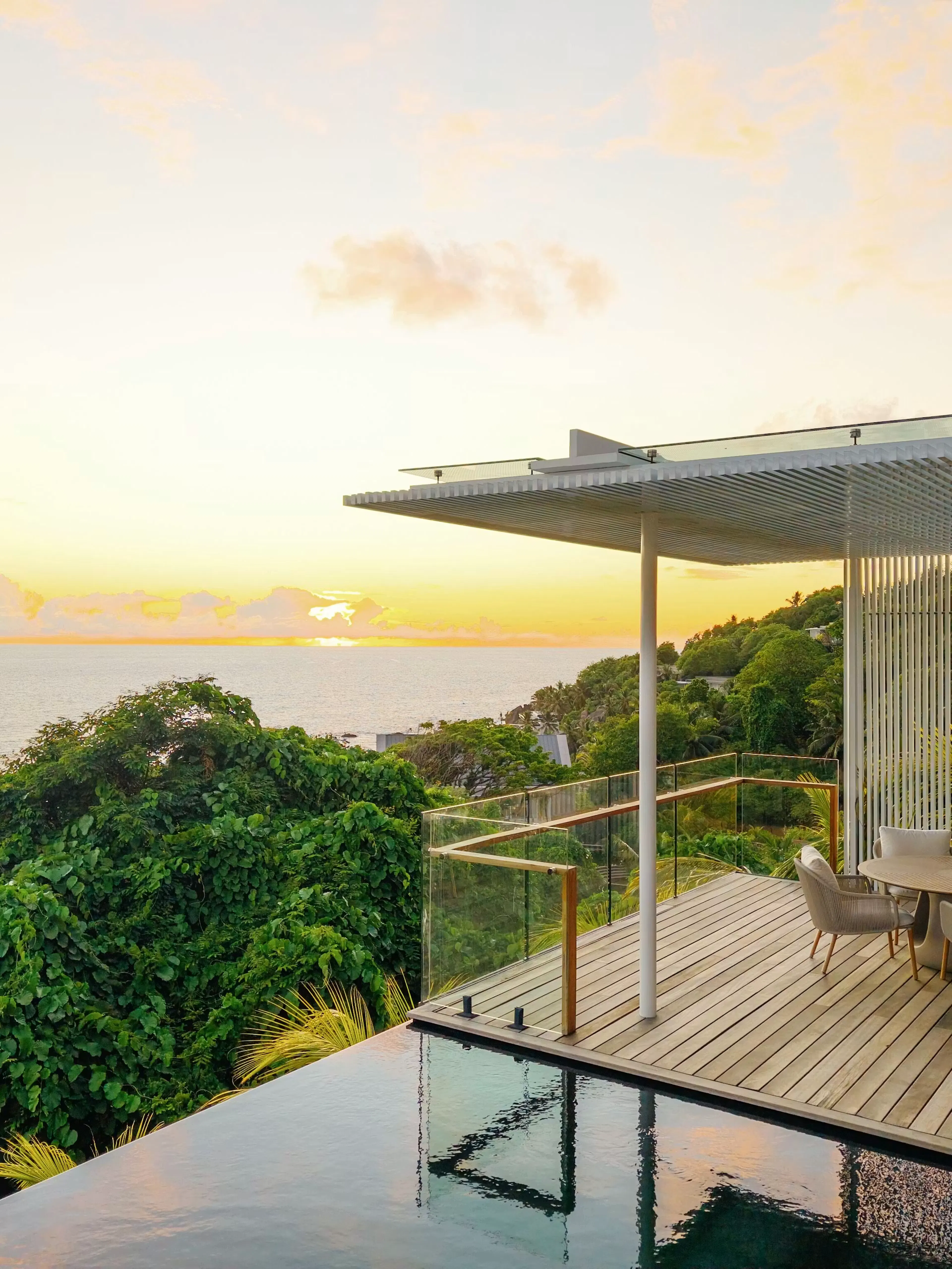 Modern outdoor patio overlooking lush greenery at sunset.