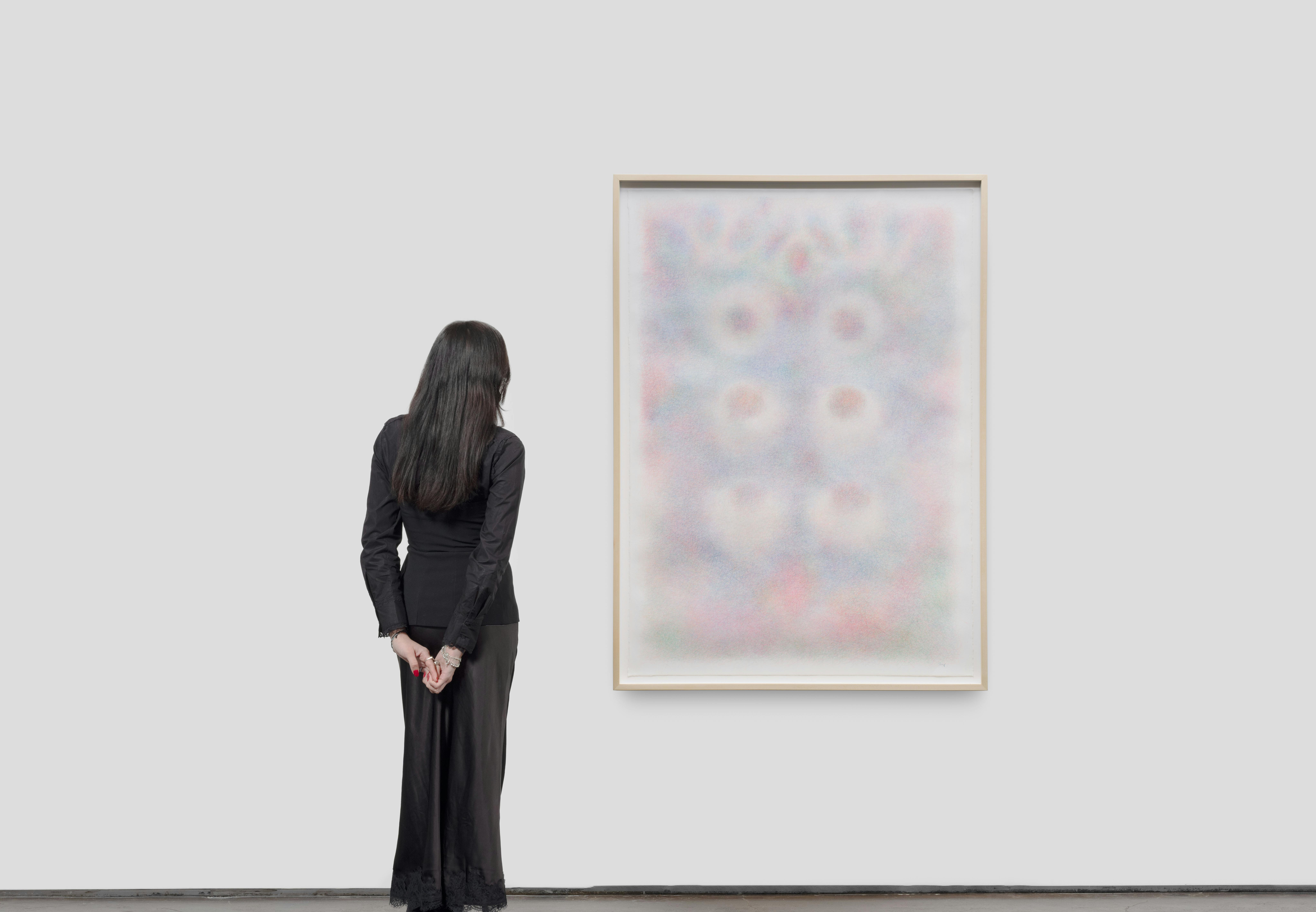 Installation view of Blue, Iris by Sheng Lor from the exhibition Interstitial at Gallery Sonder, showing the framed work on a white wall with a viewer standing nearby for scale.