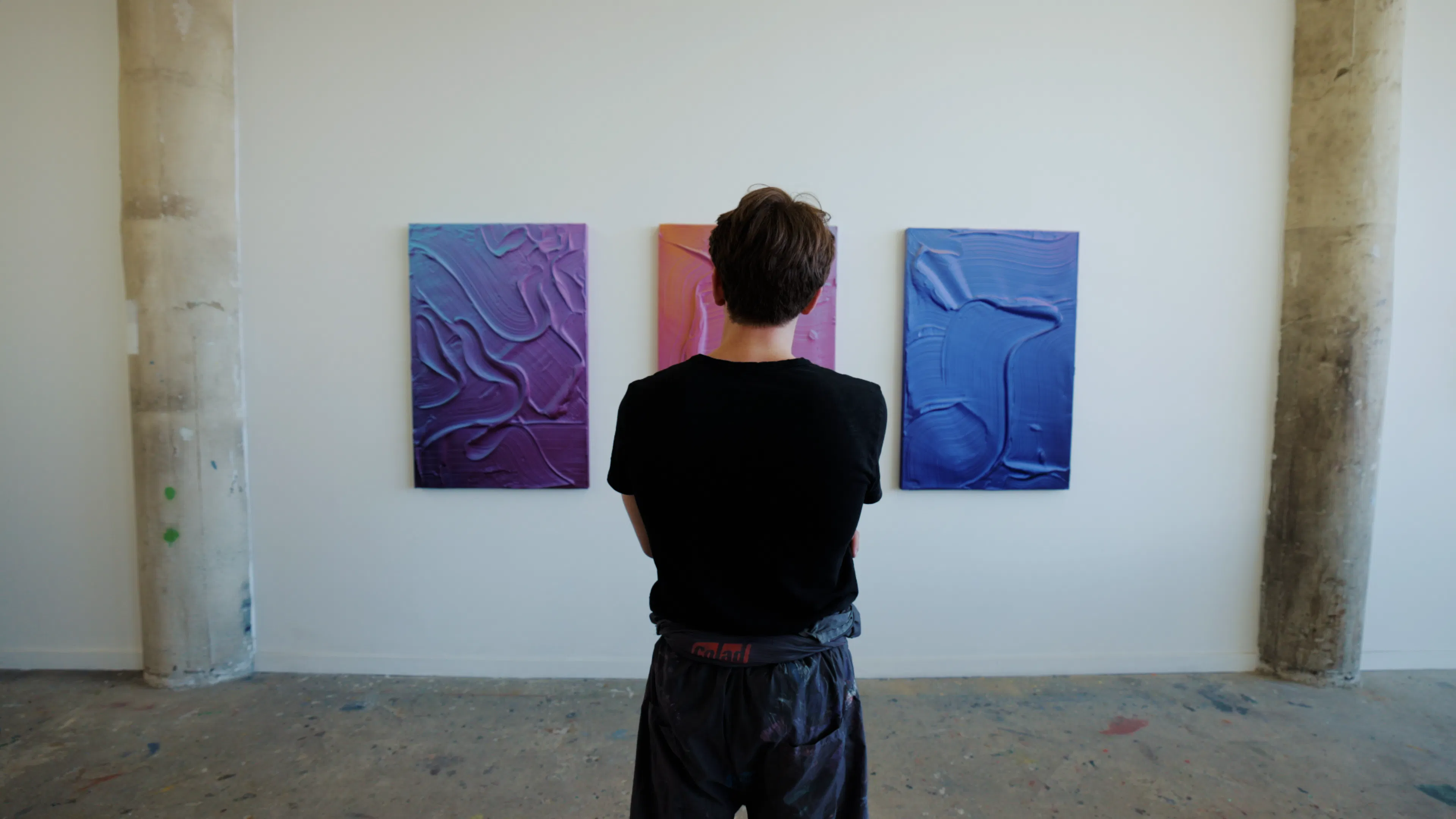 Ruben Benjamin stands in his Los Angeles studio viewing three textured abstract paintings created for the exhibition After The Dust Settles.