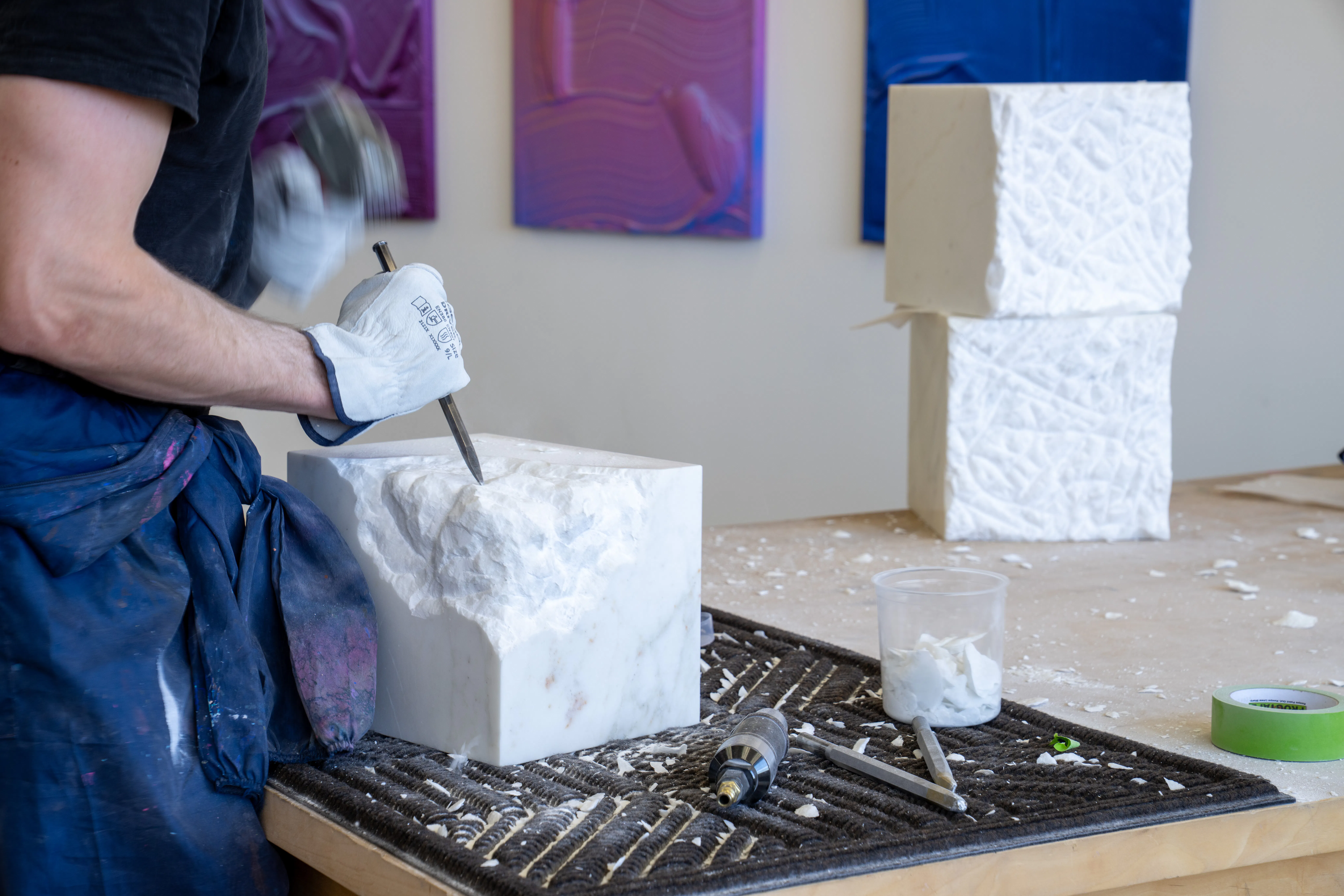Ruben Benjamin at a table shaping a marble sculpture in his Los Angeles residency studio.