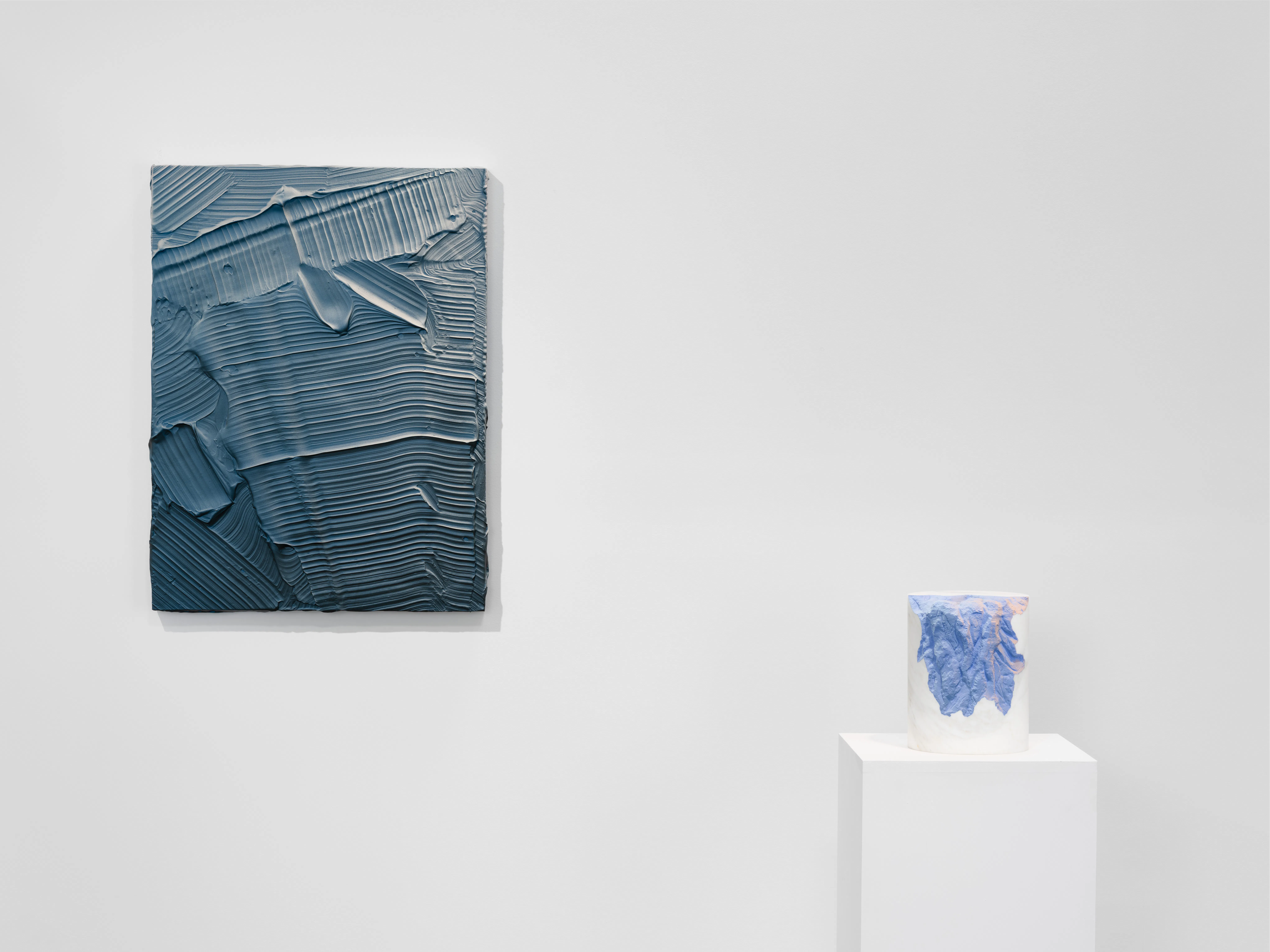 Ruben Benjamin, After The Dust Settles, 2026 — installation view at Gallery Sonder showing a large blue impasto painting mounted on the wall alongside a sculptural work displayed on a pedestal, emphasizing material continuity and variation between wall-based and three-dimensional forms. Gallery Sonder, Orange County.
