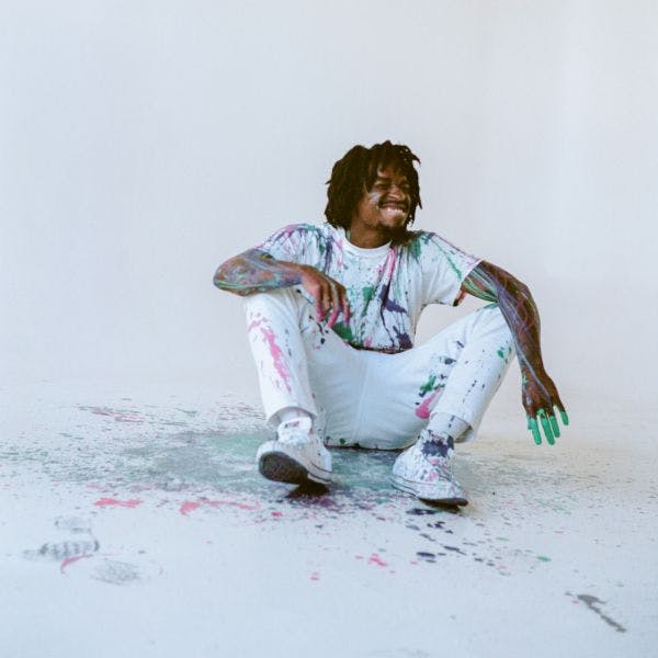 artist sitting on the ground covered in paint 