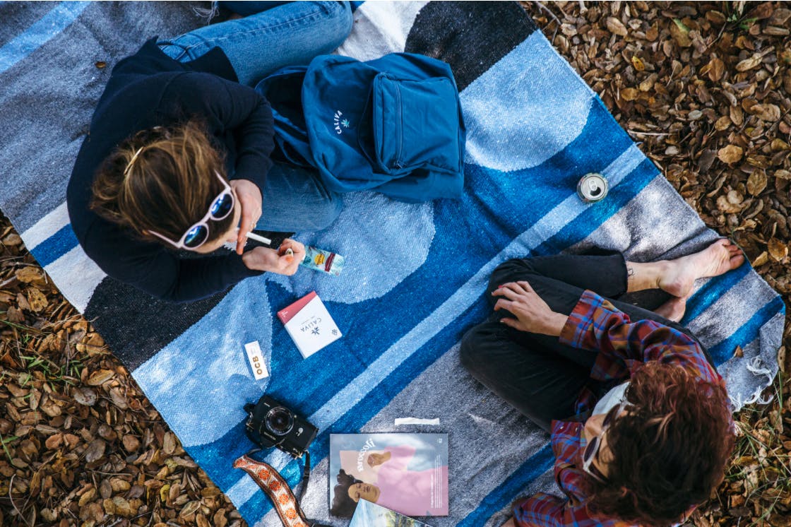 two people sitting on a blanket with caliva products 