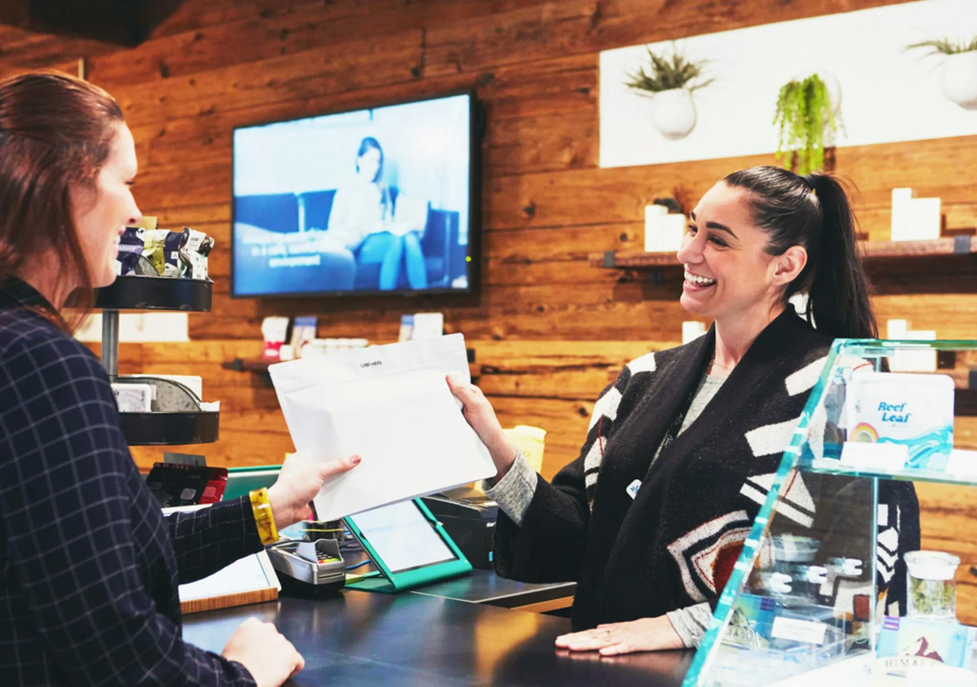 caliva employee giving customer an envelope at the dispensary 