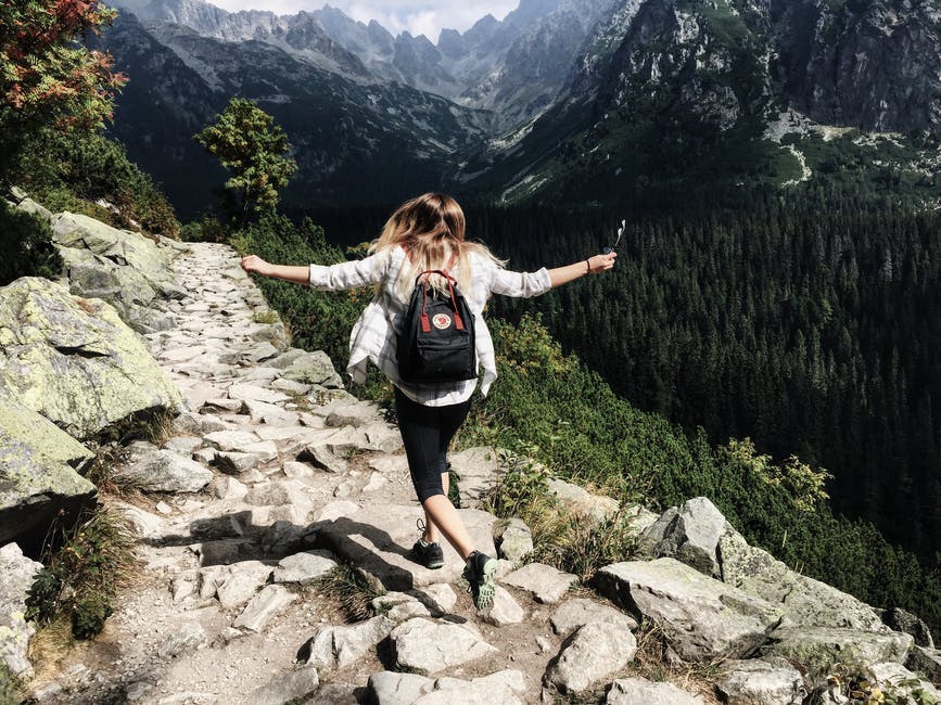 woman hiking in rocky mountains with arms extended 